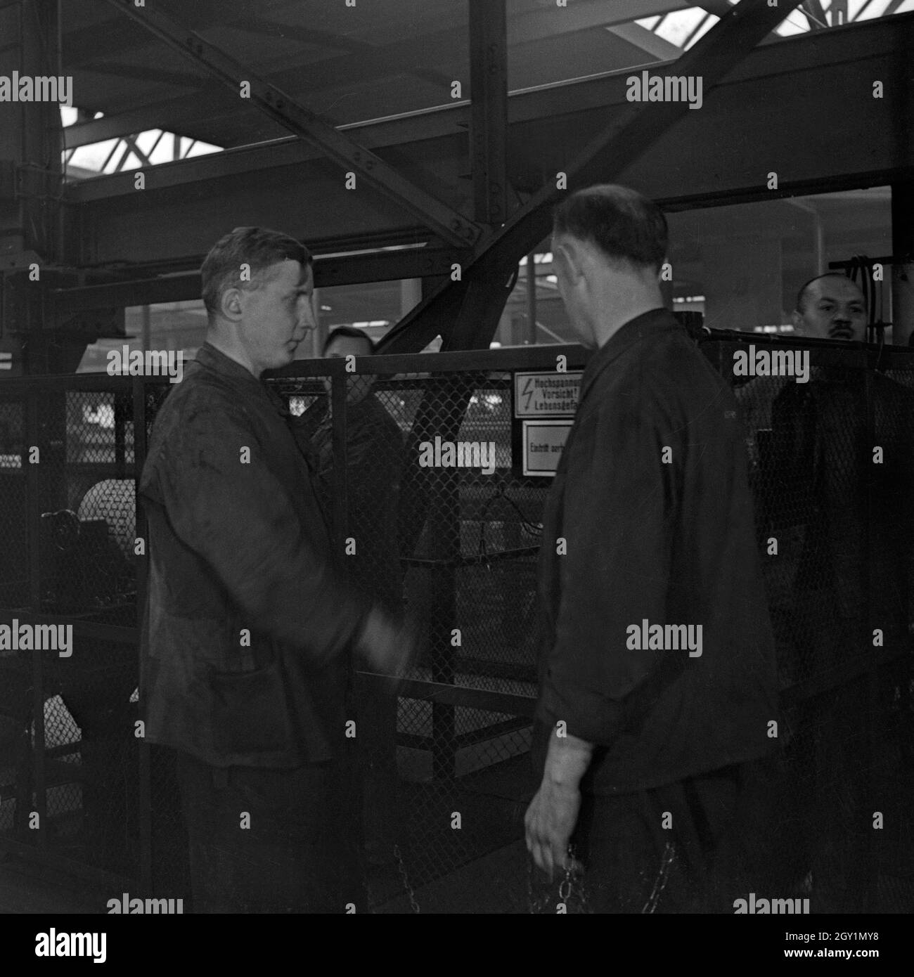 Arbeiter und Schilder zur Warnung vor Hochspannung im S-Bahn Ausbesserungswerk, Deutschland 1930er Jahre. Worker and warning signs of high voltage at a railway reparing factory, Germany 1930s. Stock Photo