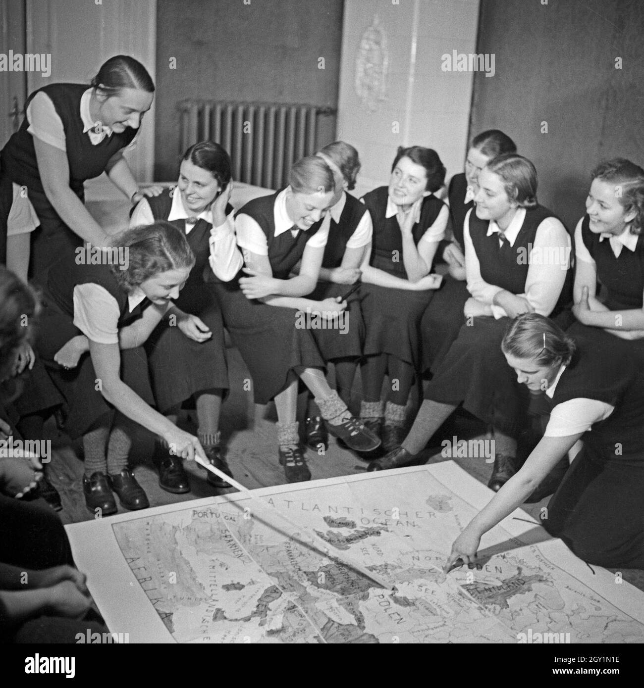 Im weltanschaulichen Unterricht diskutieren die Frauen eine Europakarte beim weiblichen Arbeitsdienst in Molkenberg bei Fürstenwalde, Deutschland 1930er Jahre. Women discussing a map of Europe in their ideological lesson at the female workforce group of Molkenberg, Germany 1930s. Stock Photo