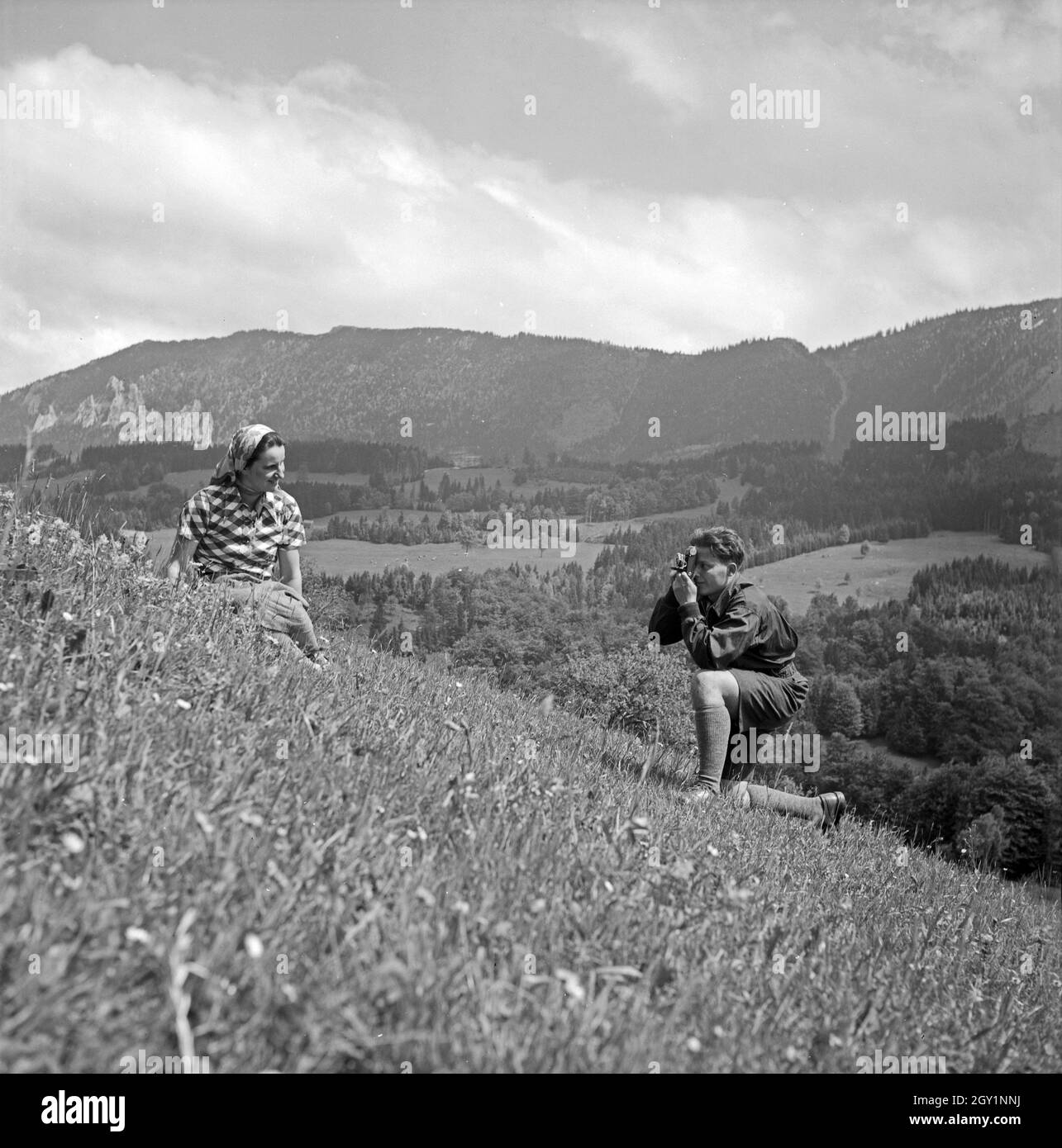 Ein junger Mann fotografiert eine junge Frau in einer Berglandschaft ...