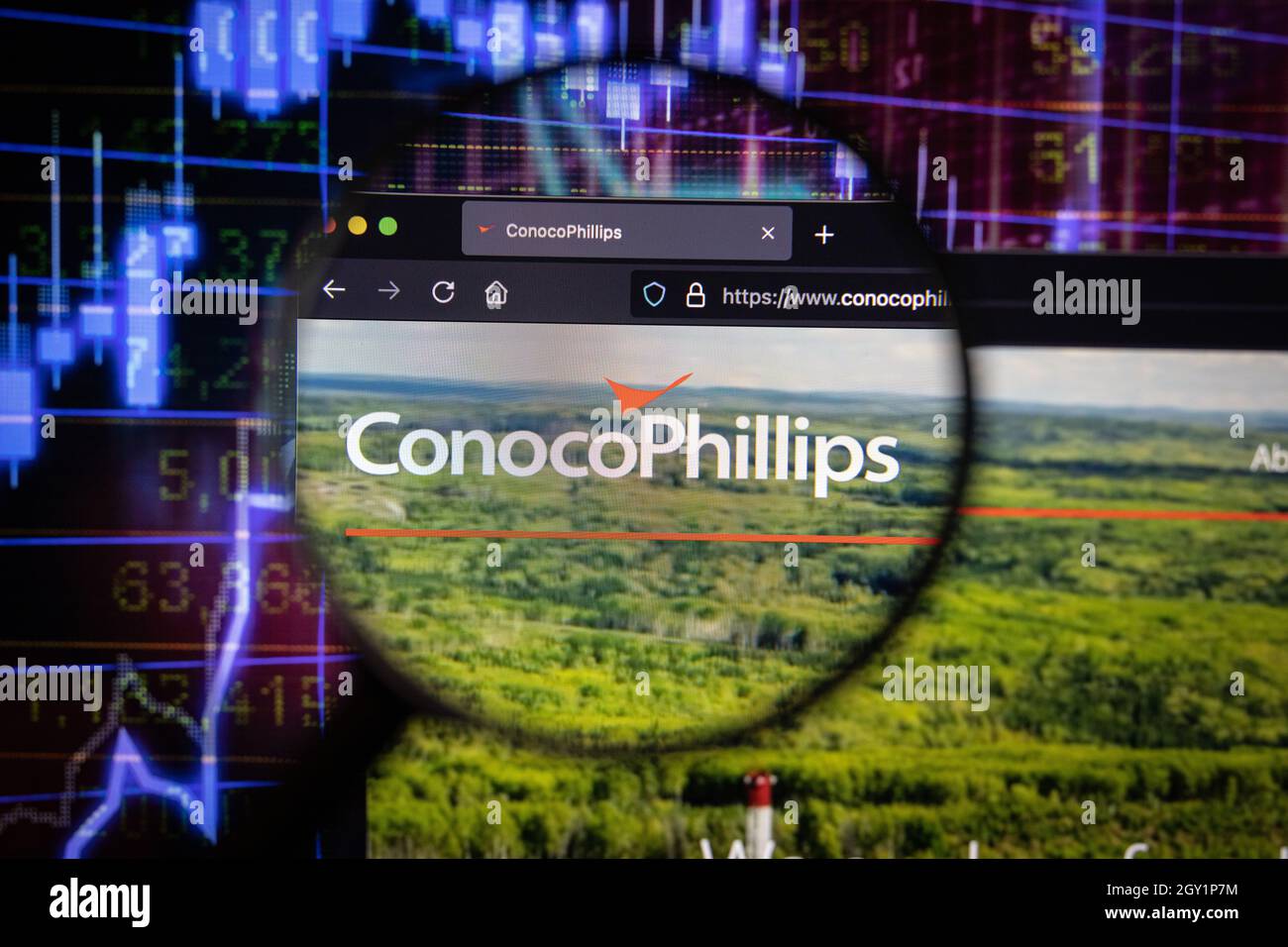ConocoPhillips company logo on a website with blurry stock market developments in the background, seen on a computer screen through a magnifying glass Stock Photo