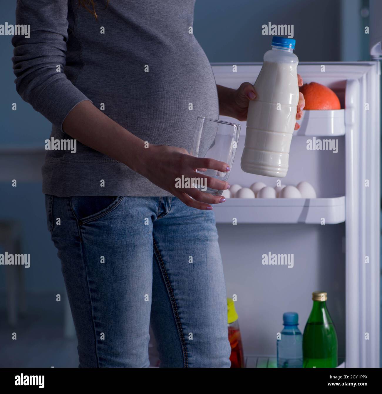 The pregnant woman near fridge looking for food and snacks at night Stock Photo
