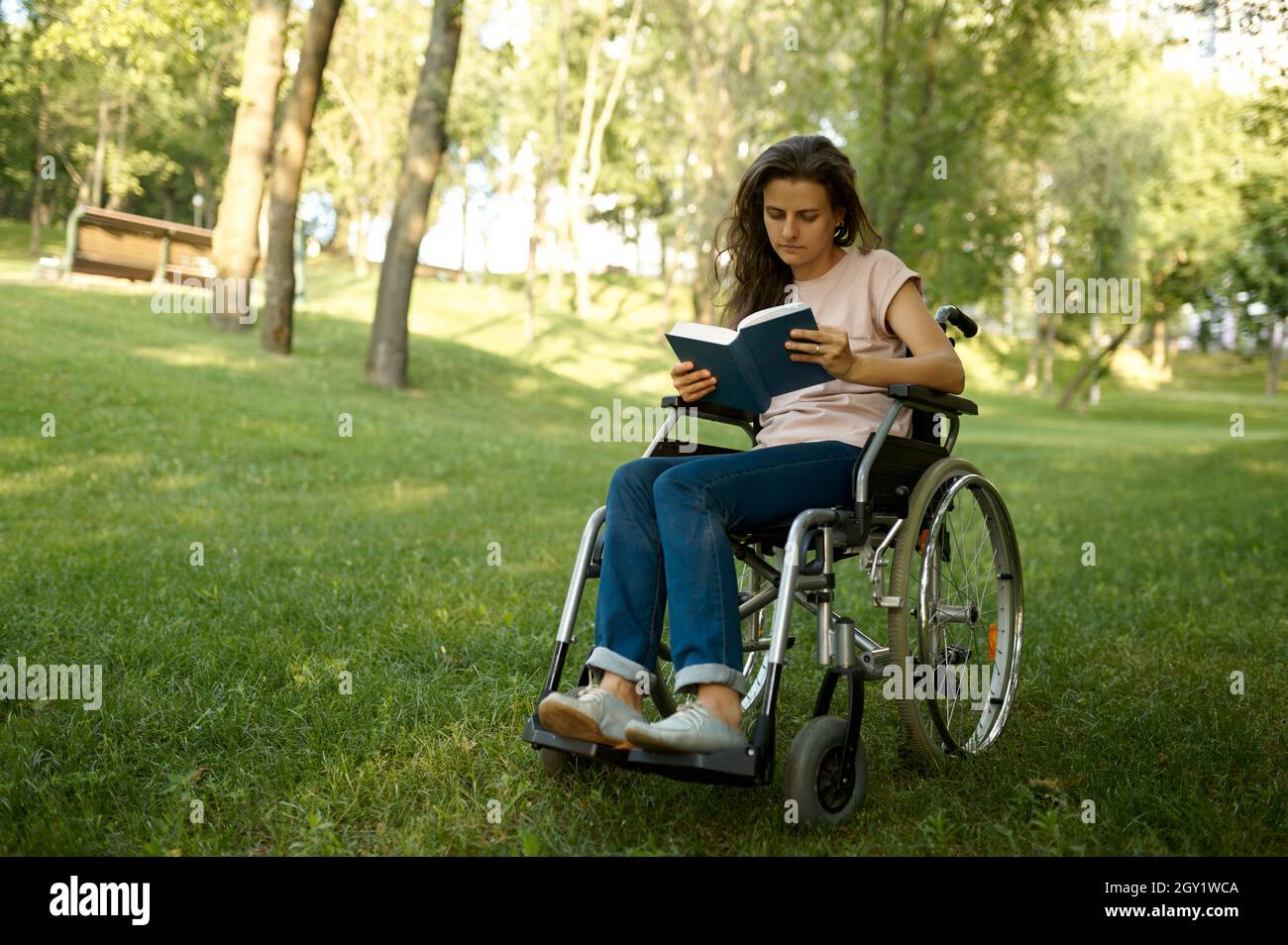 Disabled woman in wheelchair reading book in park Stock Photo Alamy