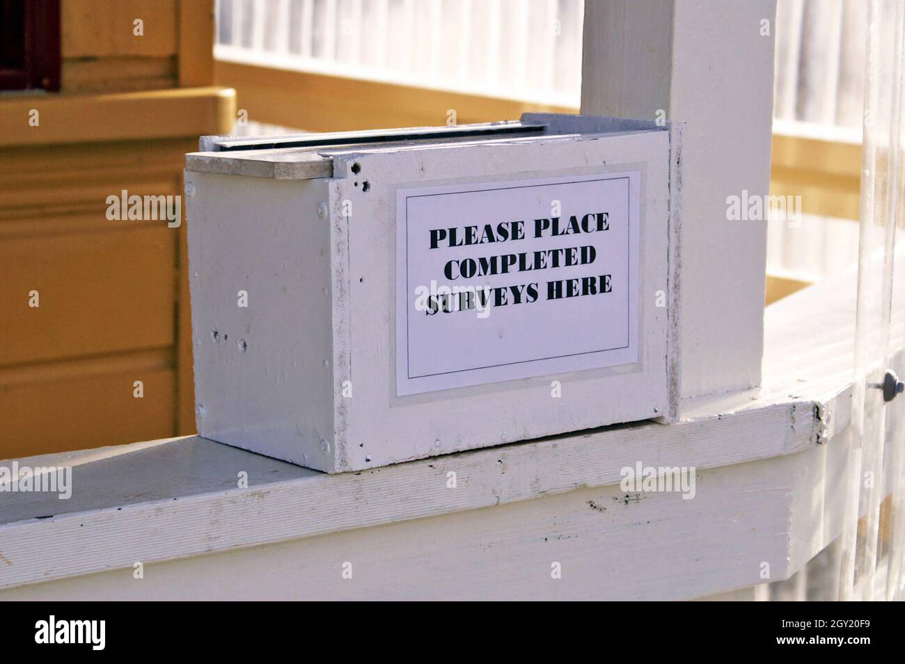 A wooden box placed at the exit of an attraction in New Zealand requests to place their completed paper surveys in it.  The box states 'Please Place Completed Surveys Here' and is an example of what is becoming an old-fashioned method of data collection. Stock Photo