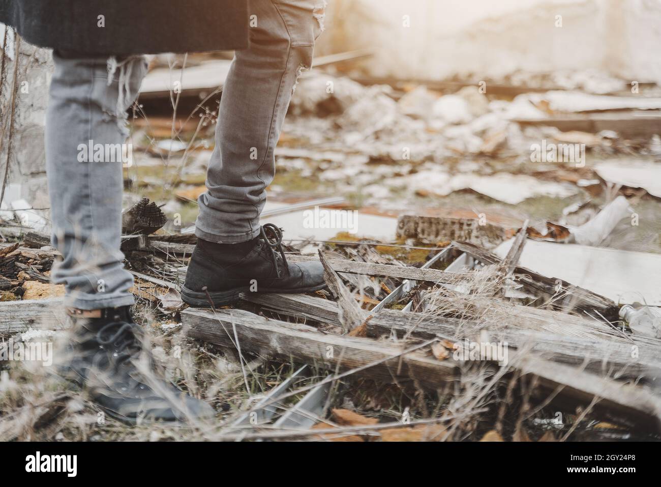 Unrecognizable young man stomping on rubble in ruins Stock Photo