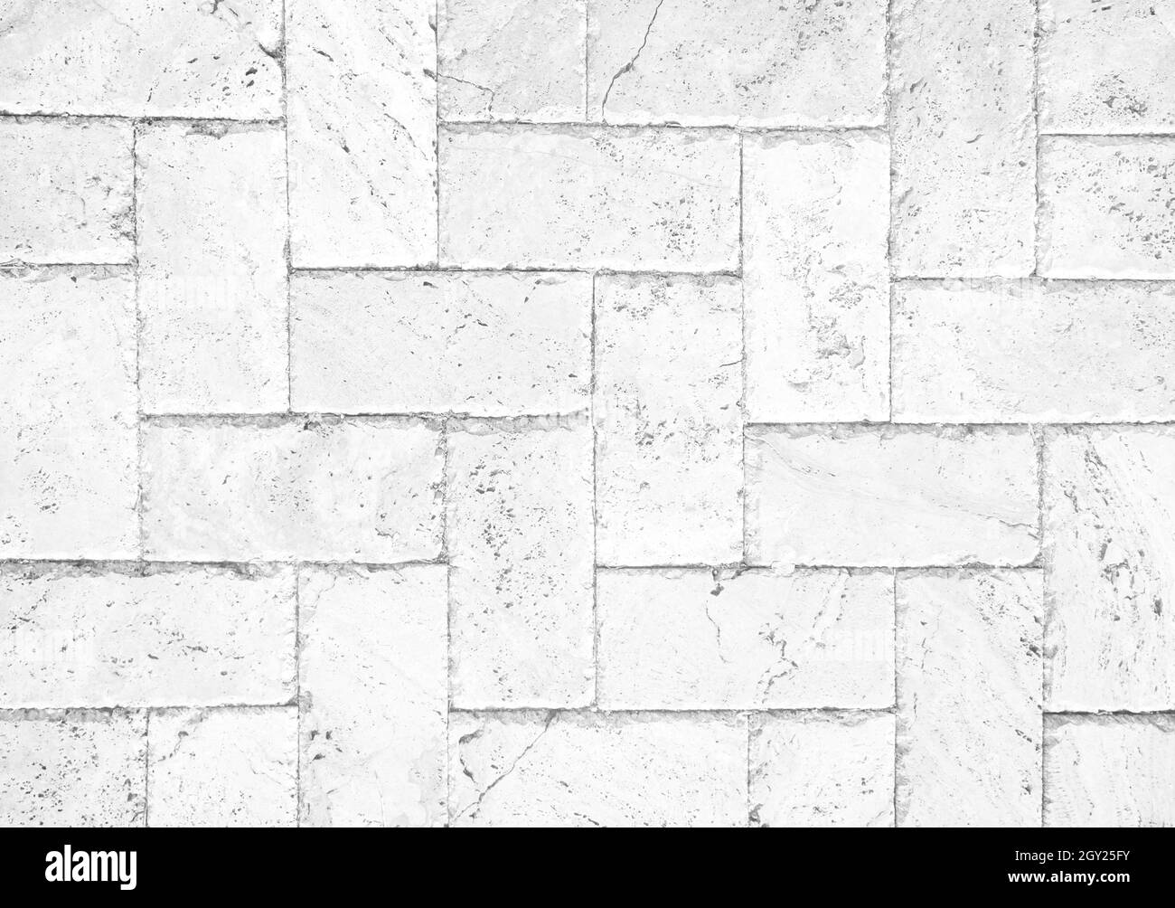 Gray white brick sidewall pavers. Stones laid down on ground pavement walkway. Building texture flat wall. Stock Photo