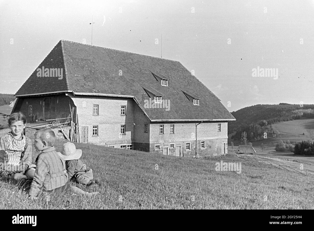 Kinder auf der Wiese vor dem Furtwängler Hof im Schwarzwald, Deutschland 1930er Jahre. Children sitting on a field in front of the Furtwängler Hof in the Black Forest, Germany 1930s. Stock Photo