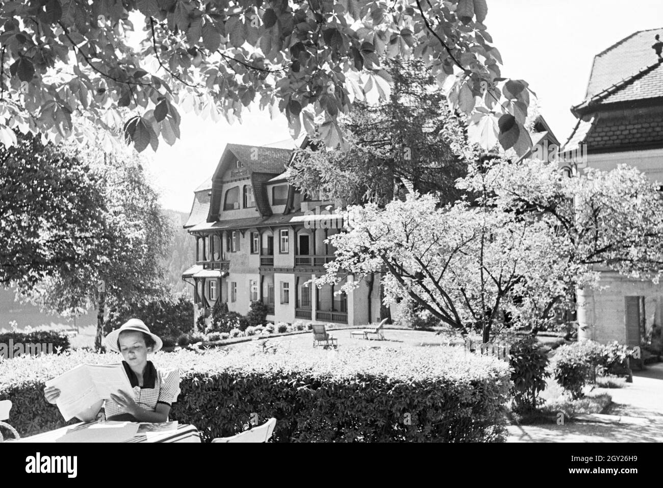 Eine junge Frau entspannt bei der Zeitschriftenlektüre im Garten, Freudenstadt, Deutschland 1930er Jahre. A young woman relaxing with a magazine in the garden, Freudenstadt, Germany 1930s. Stock Photo
