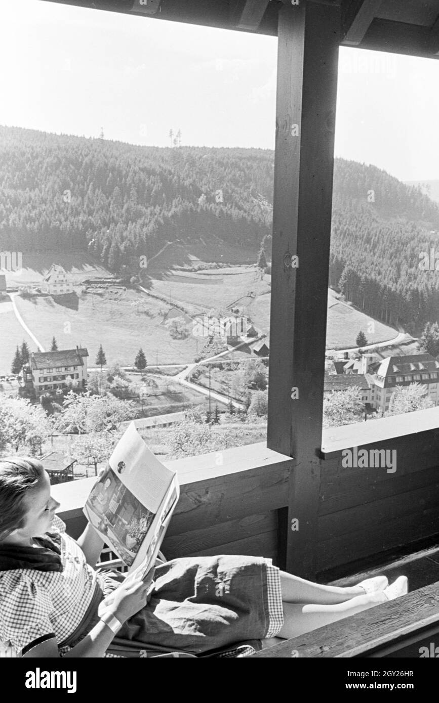 Eine junge Frau entspannt bei der Zeitschriftenlektüre auf dem Balkon, Freudenstadt, Deutschland 1930er Jahre. A young woman relaxing with a magazine on the balcony, Freudenstadt, Germany 1930s. Stock Photo