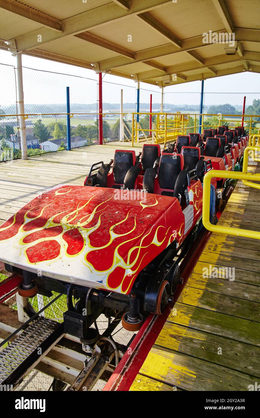 Roller coaster car with hot rod flames sits abandoned in a shielded pavilion on top of the ride Stock Photo