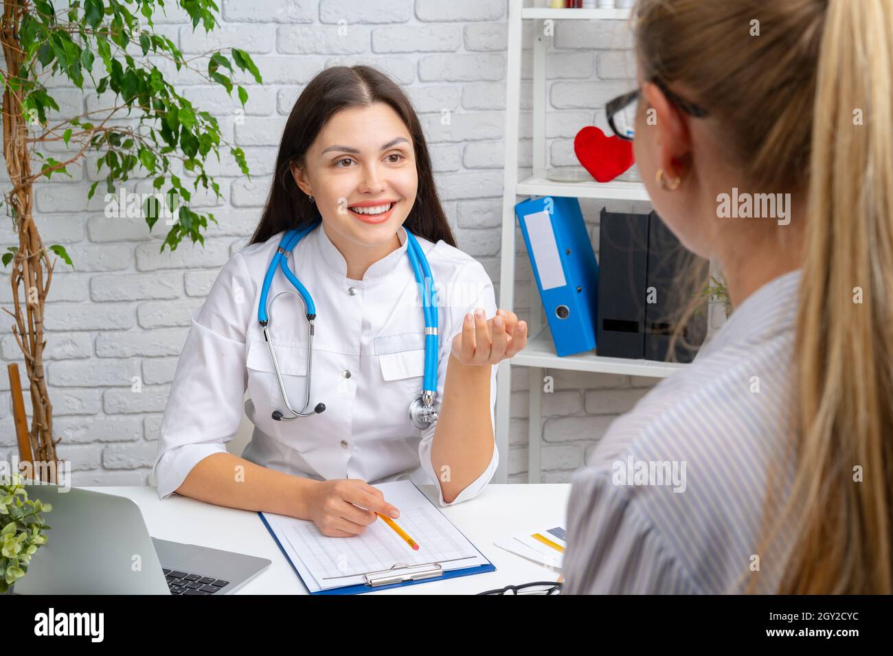 Young nice woman doctor having a conversation with her patient in ...