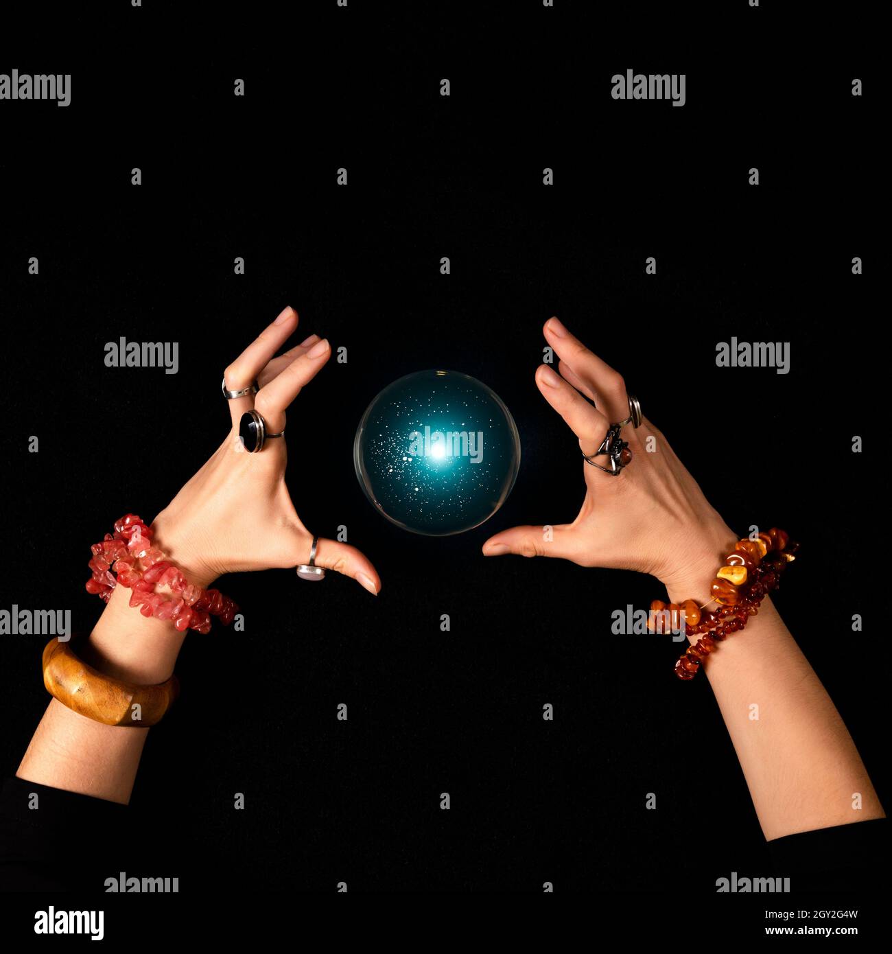 Fortune teller or witch hands and a glowing magic ball isolated on dark