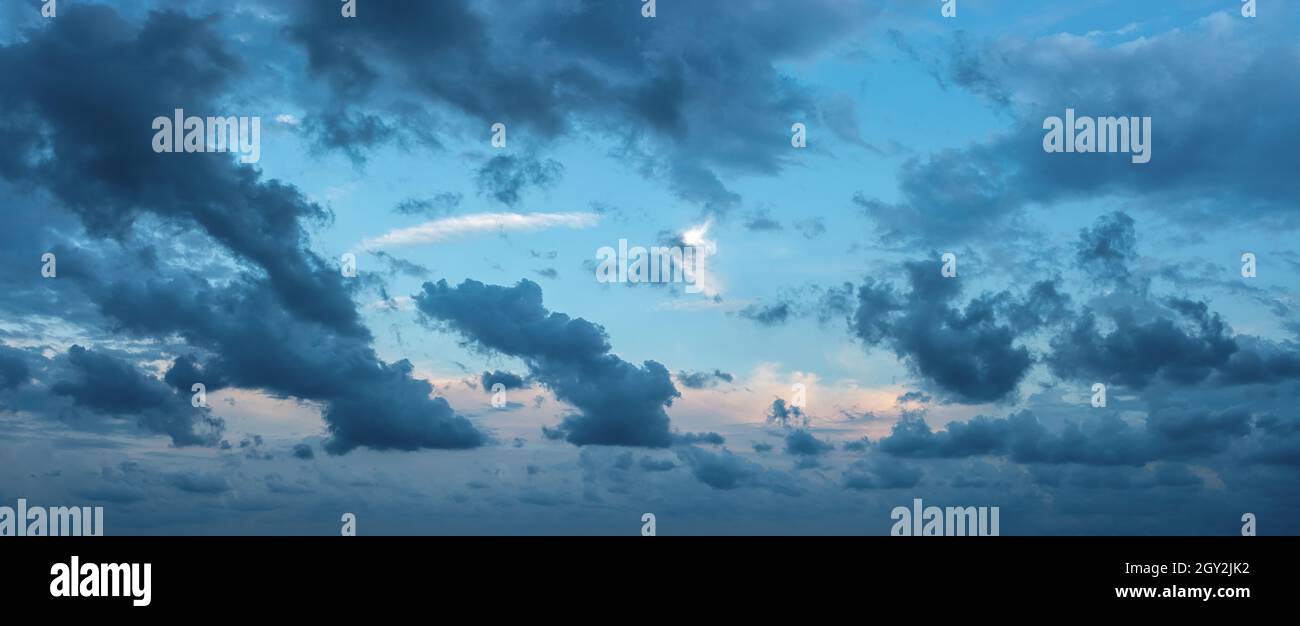 Blue stormy clouds blown by the strong wind across the sky at evening. Dramatic sky with torn dark clouds low over the horizon. Wide overcast skyscape Stock Photo