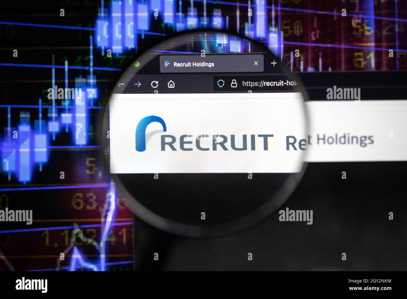 Recruit company logo on a website with blurry stock market developments in the background, seen on a computer screen through a magnifying glass Stock Photo