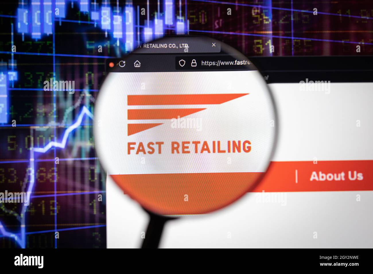 Fast Retailing company logo on a website with blurry stock market developments in the background, seen on a computer screen through a magnifying glass Stock Photo