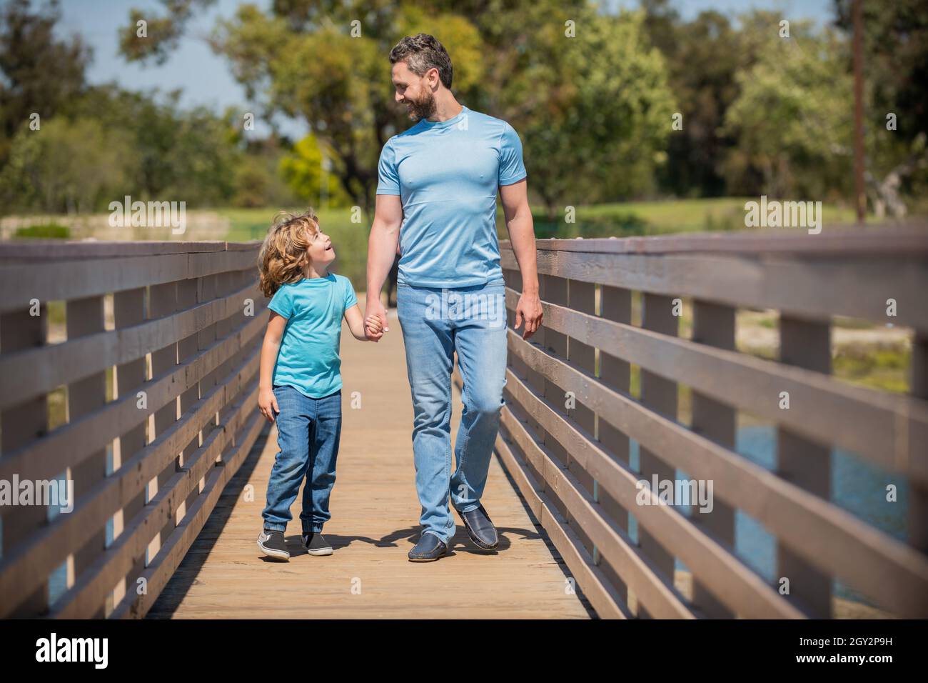 cheerful single father leading small child outside, charity Stock Photo