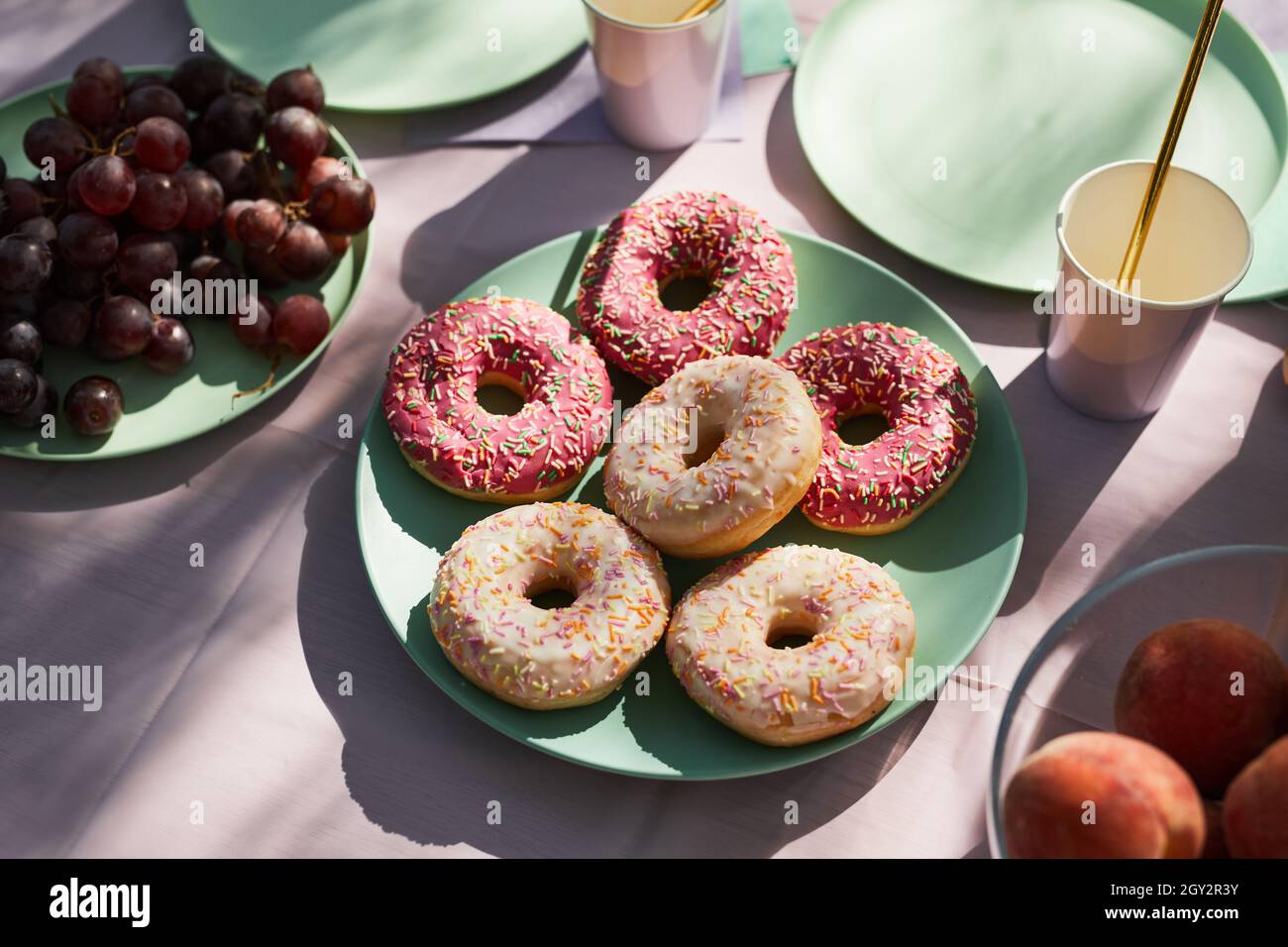 Close up of pink donuts on Summer picnic table outdoors decorated for Birthday party, copy space Stock Photo