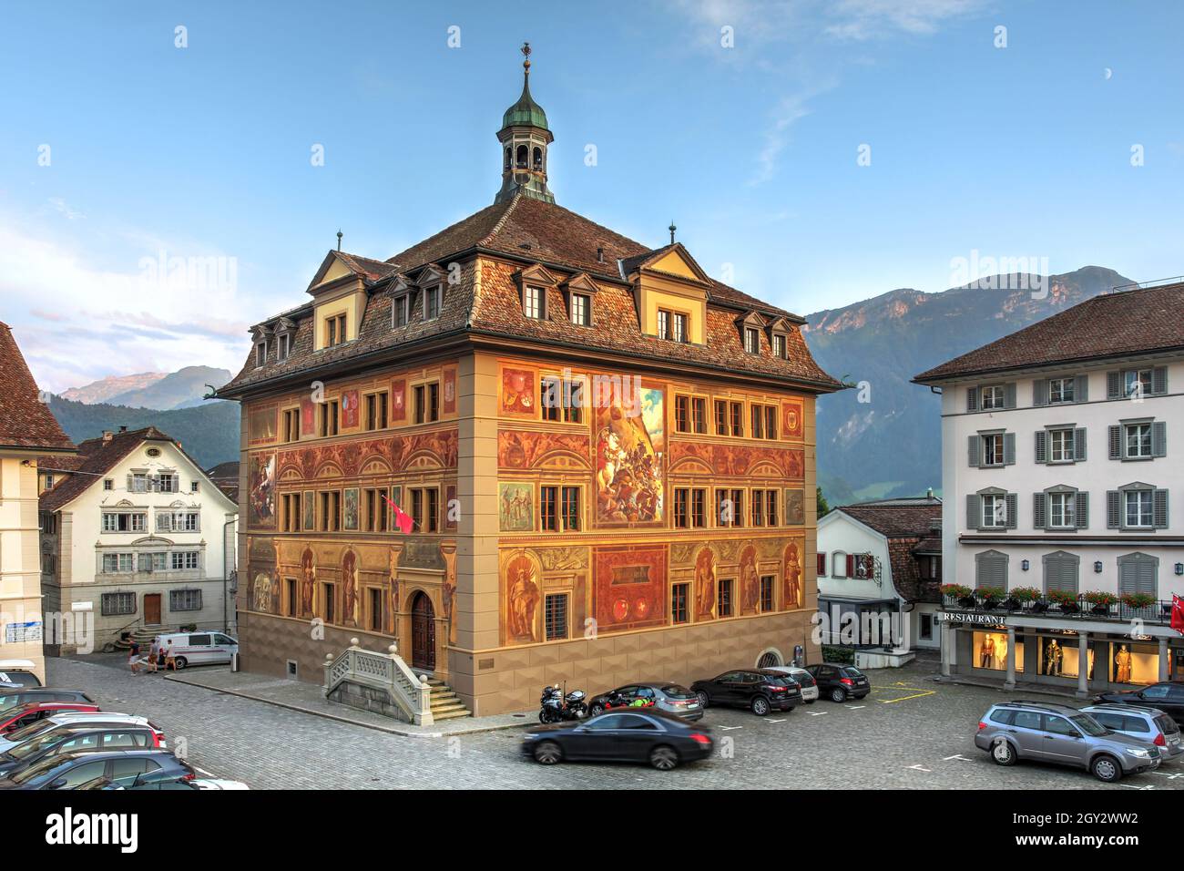 The Town Hall (Rathaus) of Schwyz city in central Switzerland with distinctive murals dominating the Hauptplatz square during a summer evening. Stock Photo