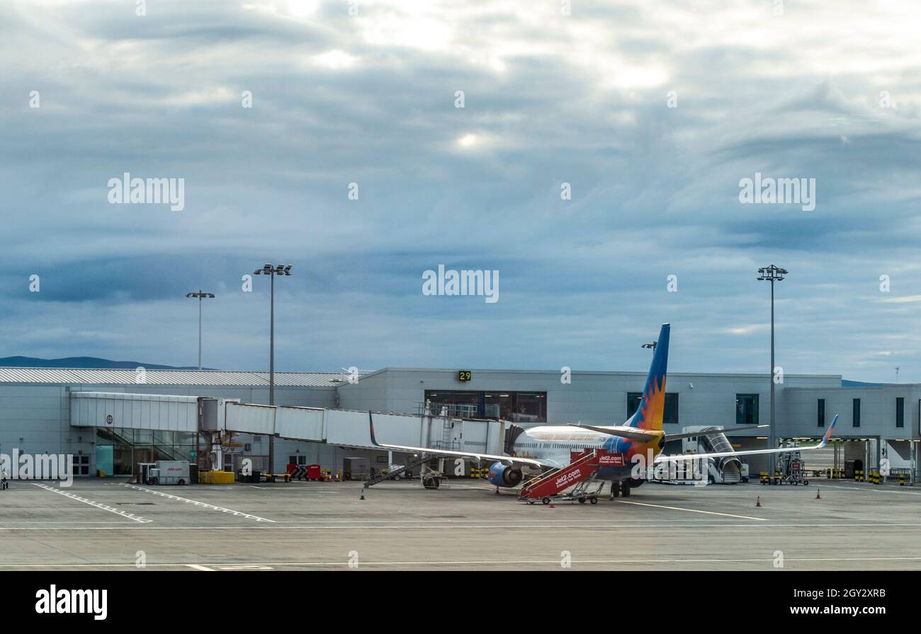 A Boeing 737-800 in the livery of Jet2 standing on an apron in Glasgow Airport, Scotland. A jet bridge is attached. Stock Photo