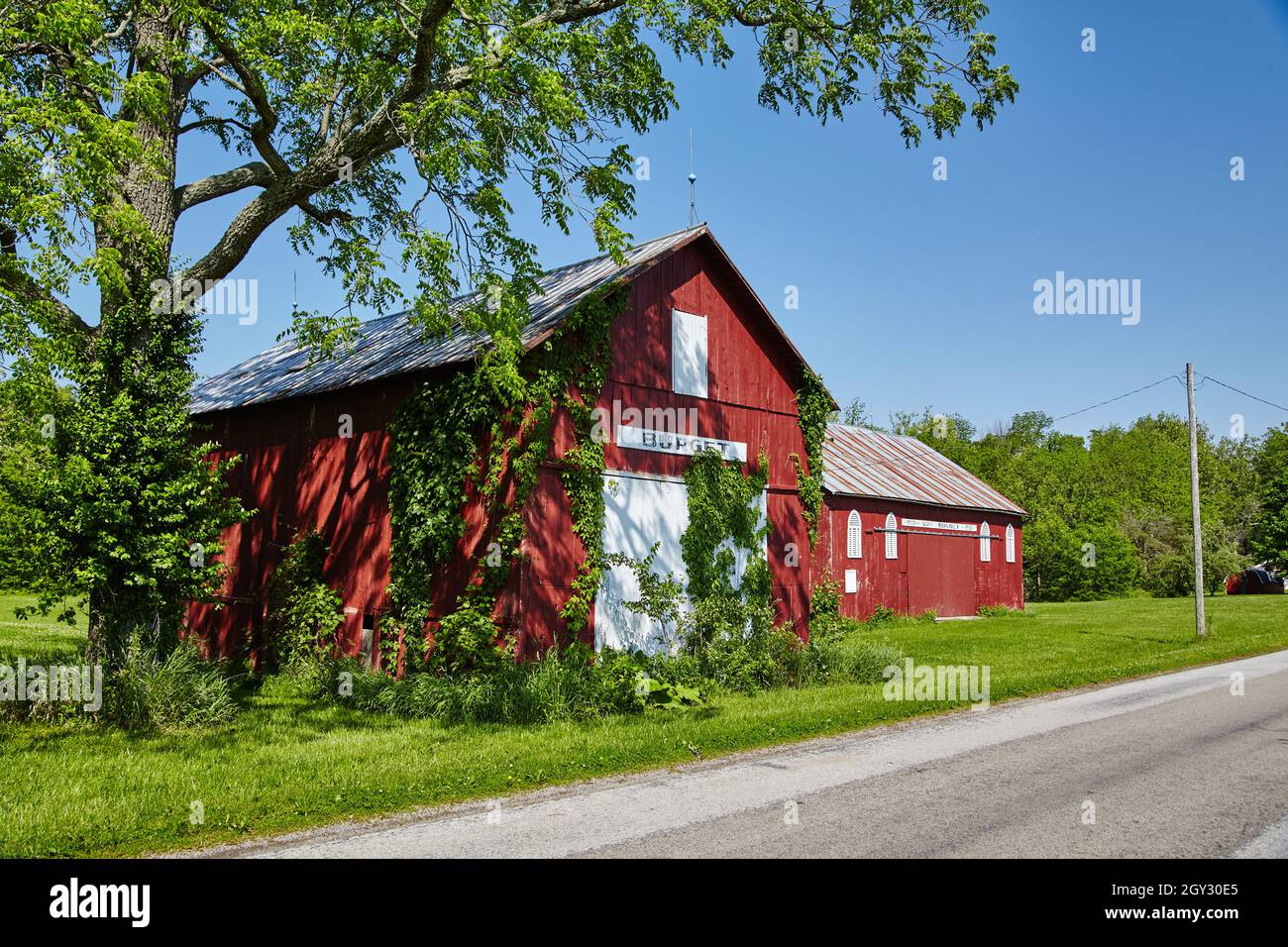 Red and white farmhouse and barn on the side of the road next to some ...
