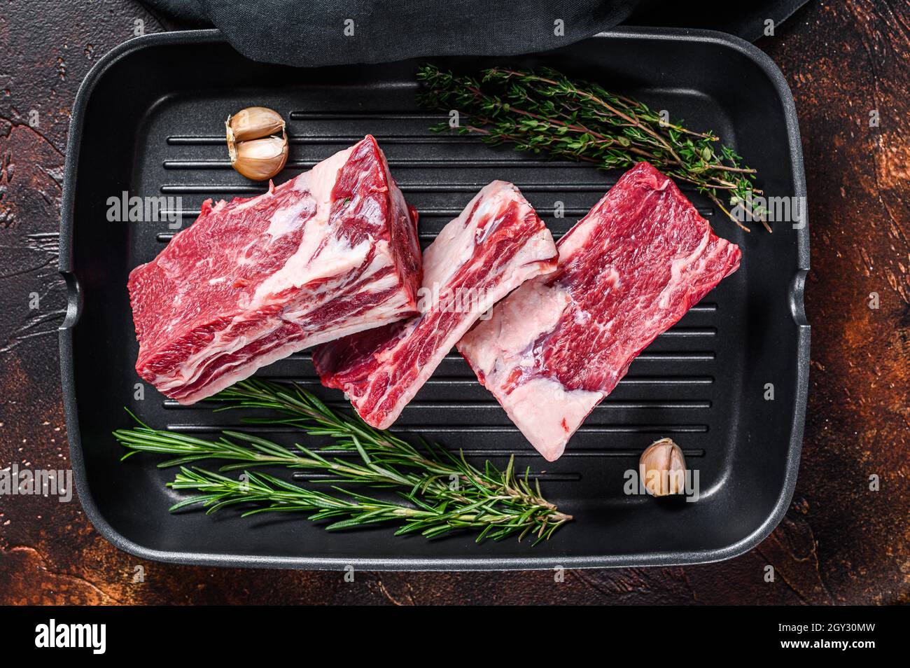 Beef calf short ribs meat in a grill pan ready for cooking. Dark ...