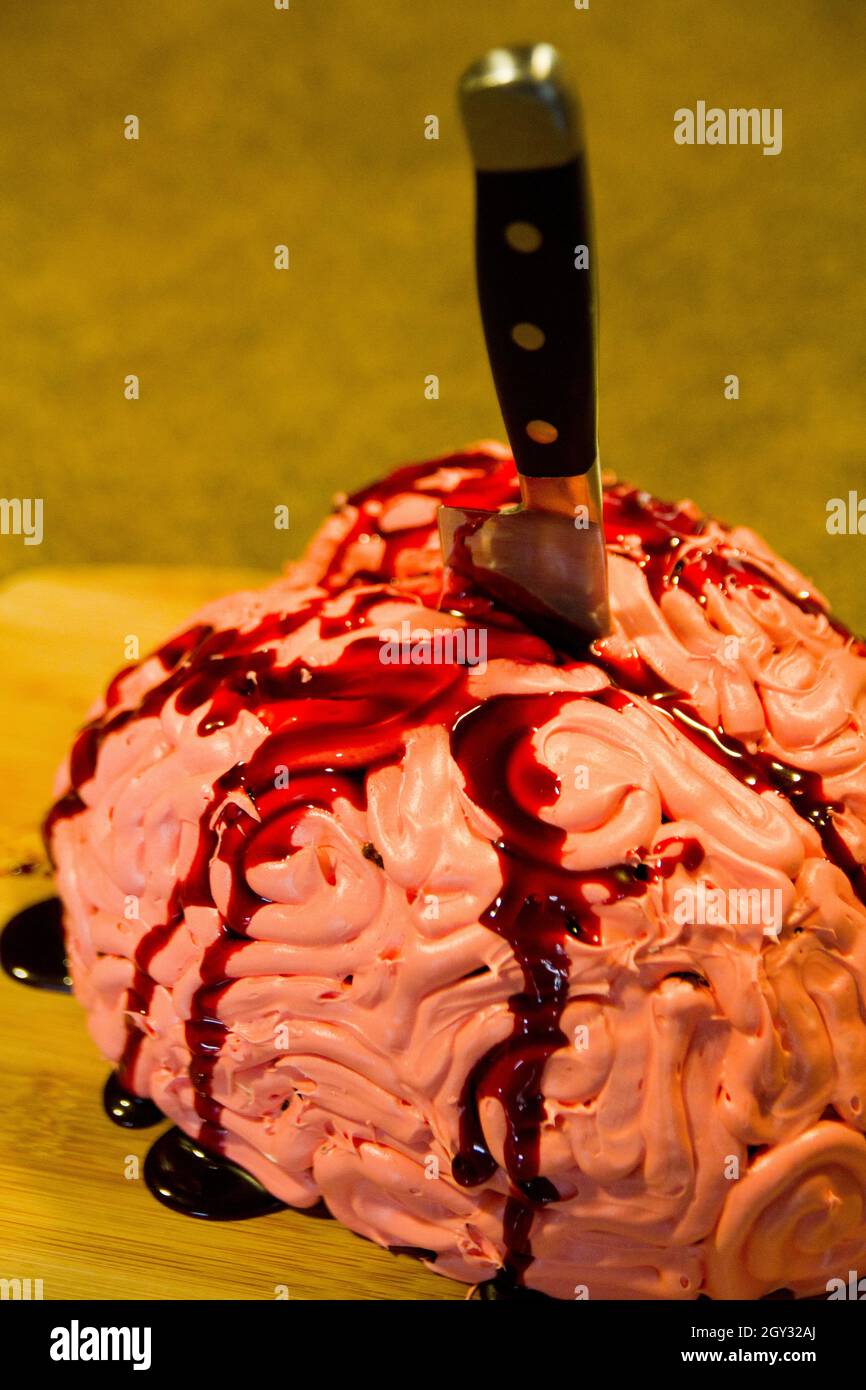 Realistic Halloween brain cake treat stabbed with a knife and flowing with red blood sauce Stock Photo