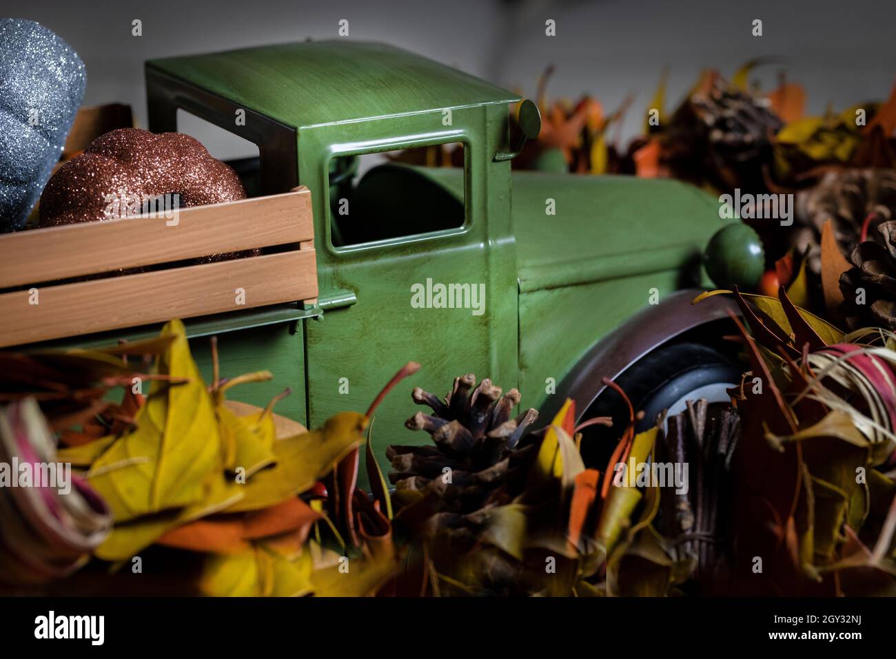 Toy harvest truck and pumpkins home decor surrounded by fall garlland for Halloween or Thanksgiving decorations Stock Photo