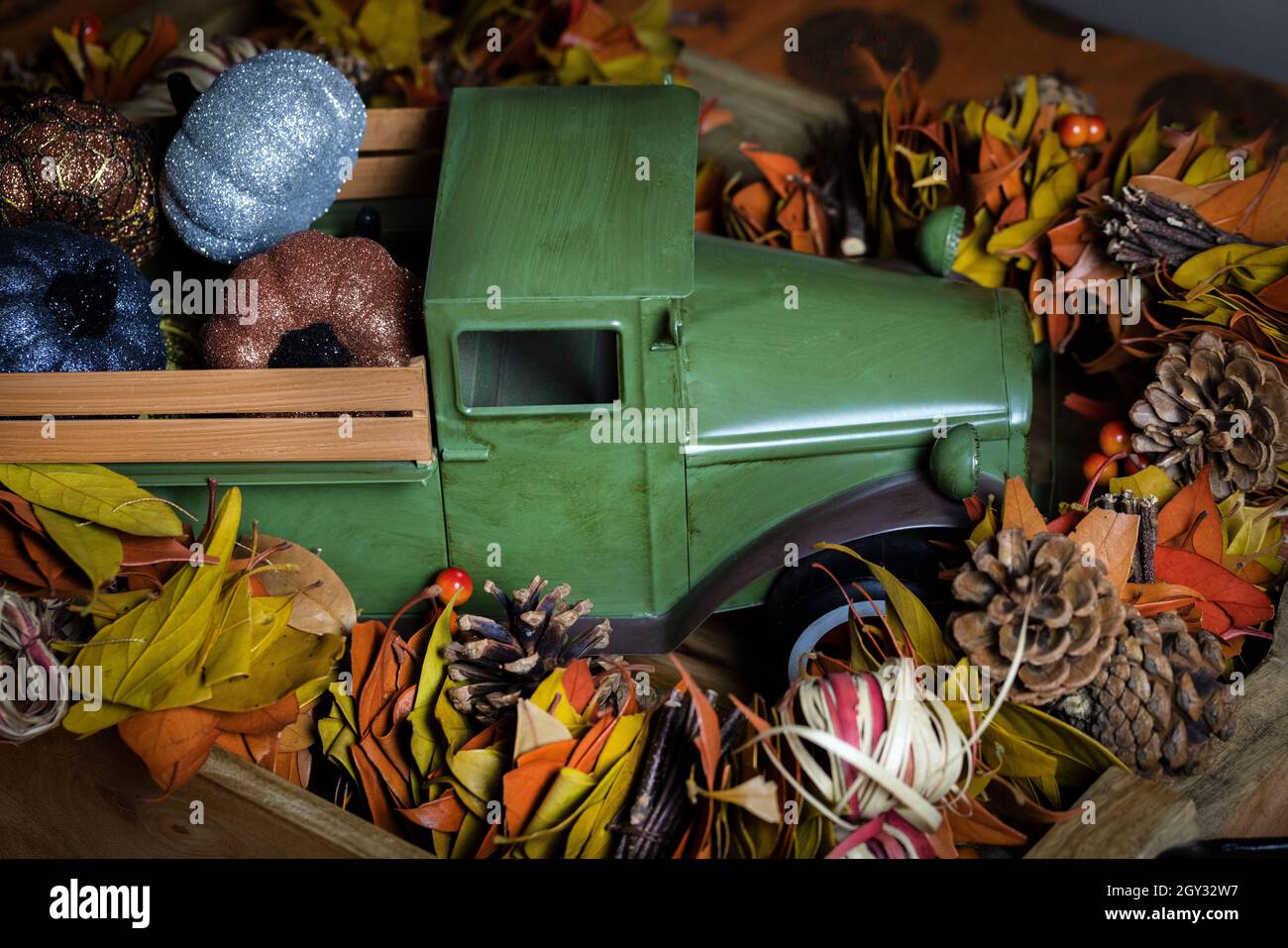 Toy harvest truck and pumpkins home decor surrounded by fall garlland for Halloween or Thanksgiving decorations Stock Photo