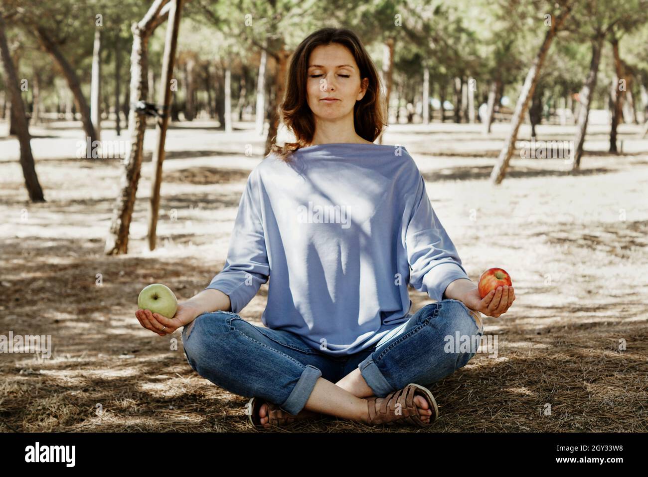 Young Spanish woman sitting in a lotus pose holding apples in a garden Stock Photo Alamy