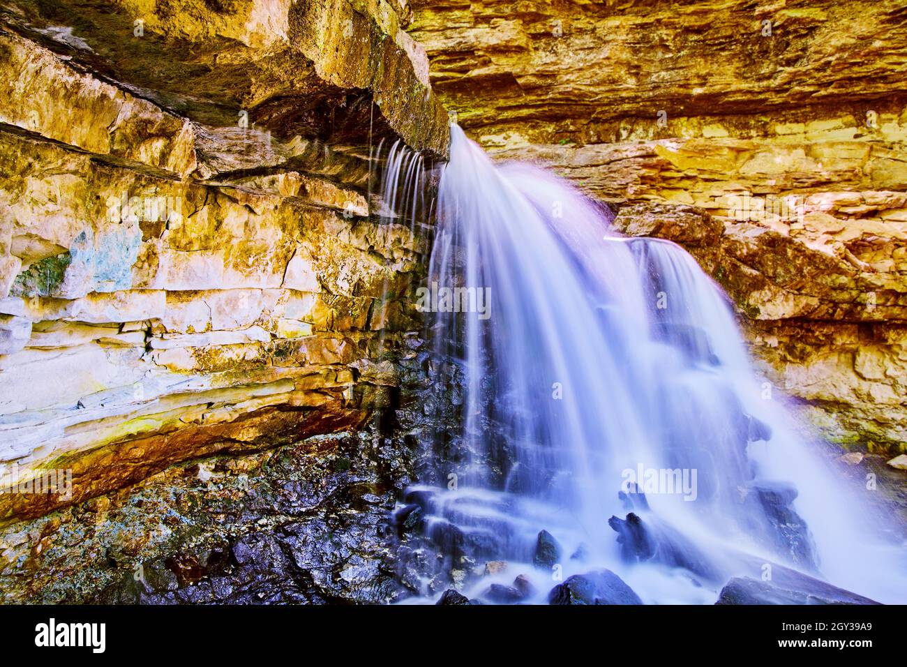 Rocky cliffs with waterfall creating gorge Stock Photo - Alamy