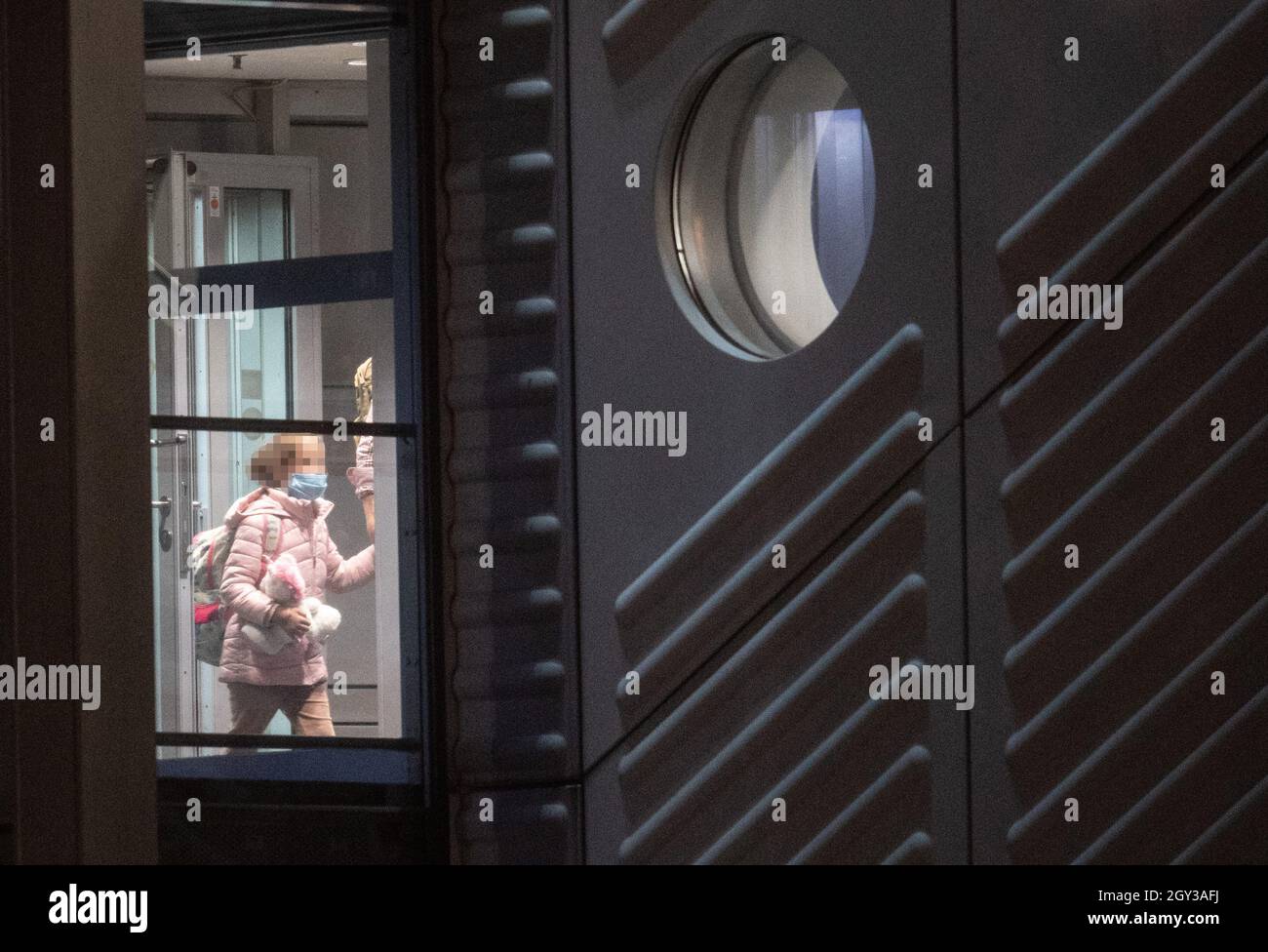 07 October 2021, Hessen, Frankfurt/Main: A small, blonde girl presses a pink soft toy against herself as she enters the area of the Federal Police at Frankfurt Airport from a charter plane. In an action that was initially kept secret, the German government, in cooperation with the US Army, had taken a total of eight German female supporters of the terrorist militia 'Islamic State' (IS) and their 23 children from a prison camp in Syria as part of a humanitarian operation. The women were brought to Germany via Kuwait on a charter plane, where almost all of them were immediately taken into custod Stock Photo