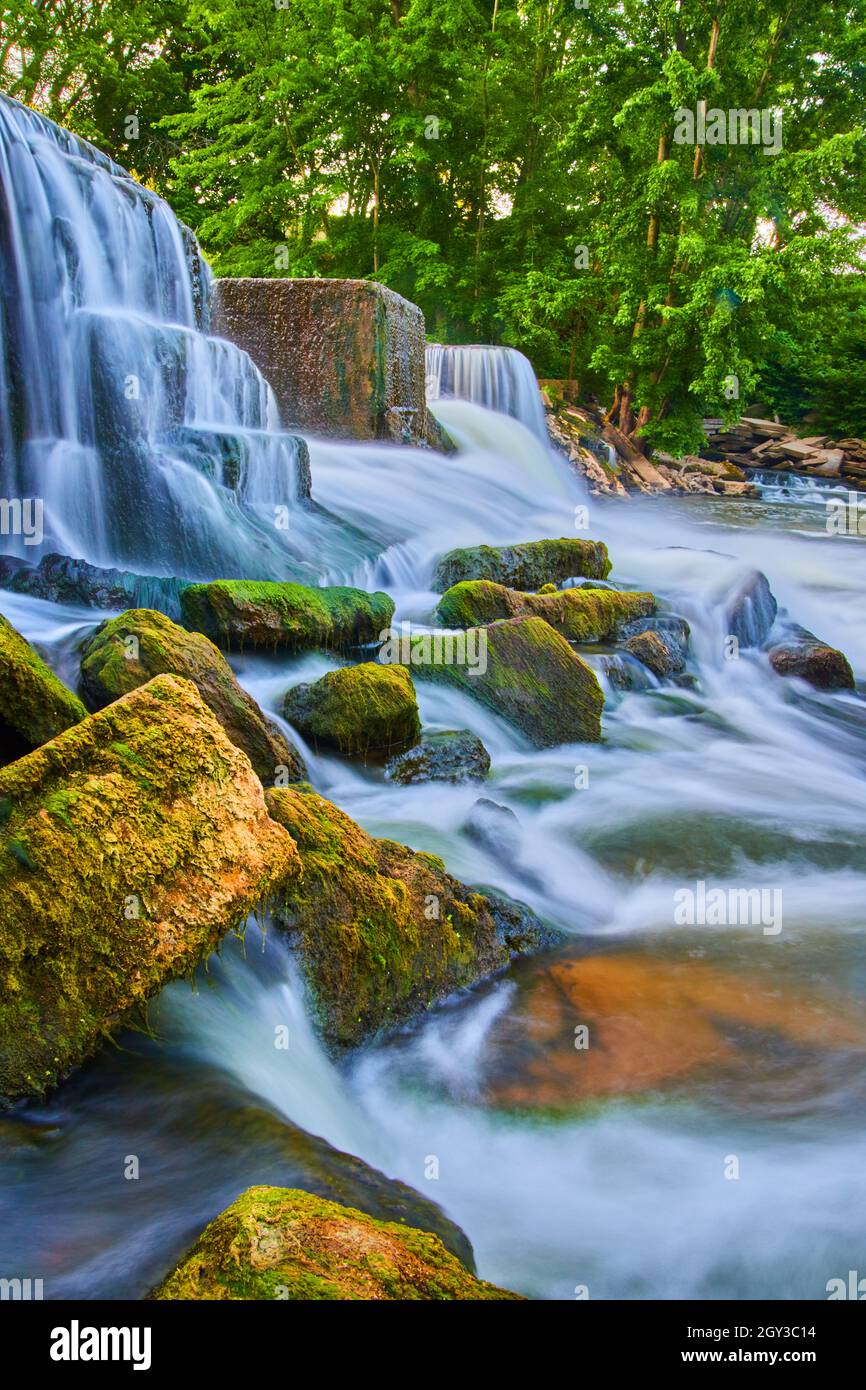 Waterfalls crashing around small algae-covered rocks Stock Photo