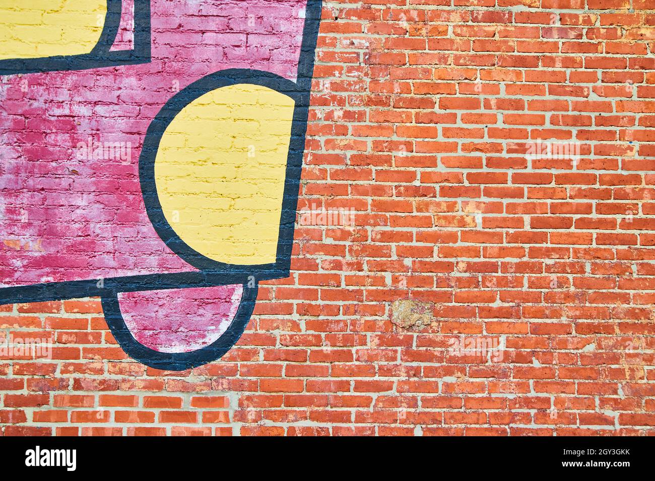 Wall of textured red brick with graffiti Stock Photo