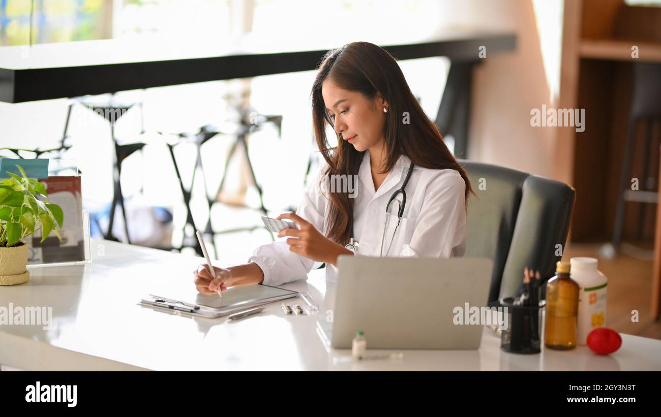 A female dentist writing a dental medicine prescriptions on digital tablet in clinic office. doctor workspace concept Stock Photo