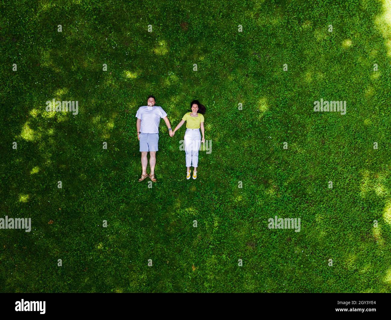 smiling couple laying down on green grass copy space Stock Photo