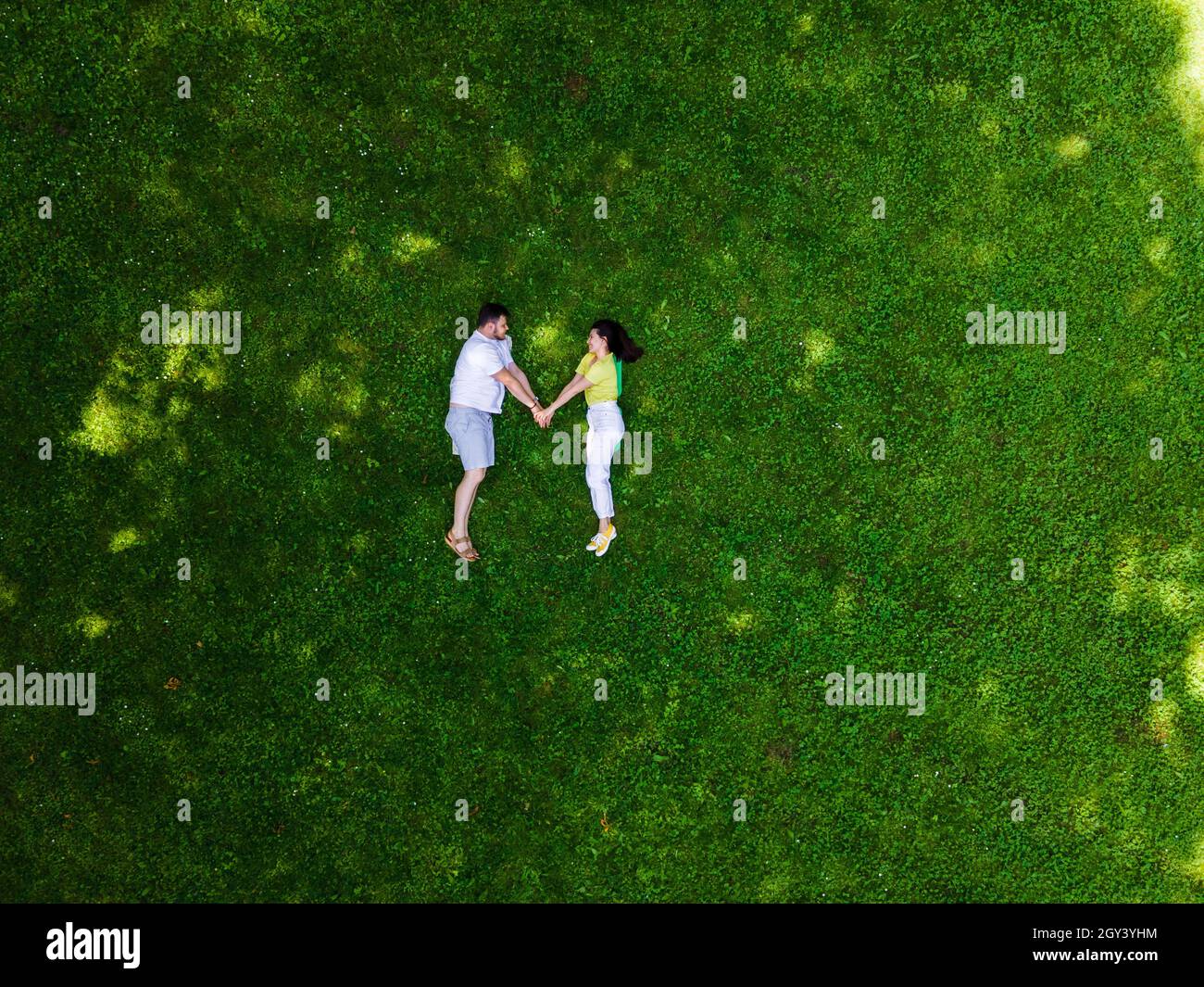smiling couple laying down on green grass copy space Stock Photo