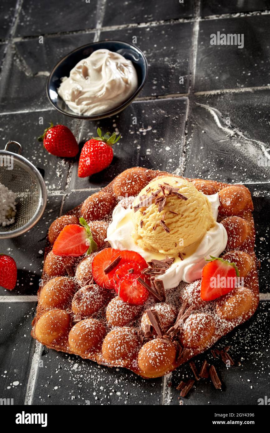 Delicious bubble waffle with ripe strawberries and whipped cream topped ...