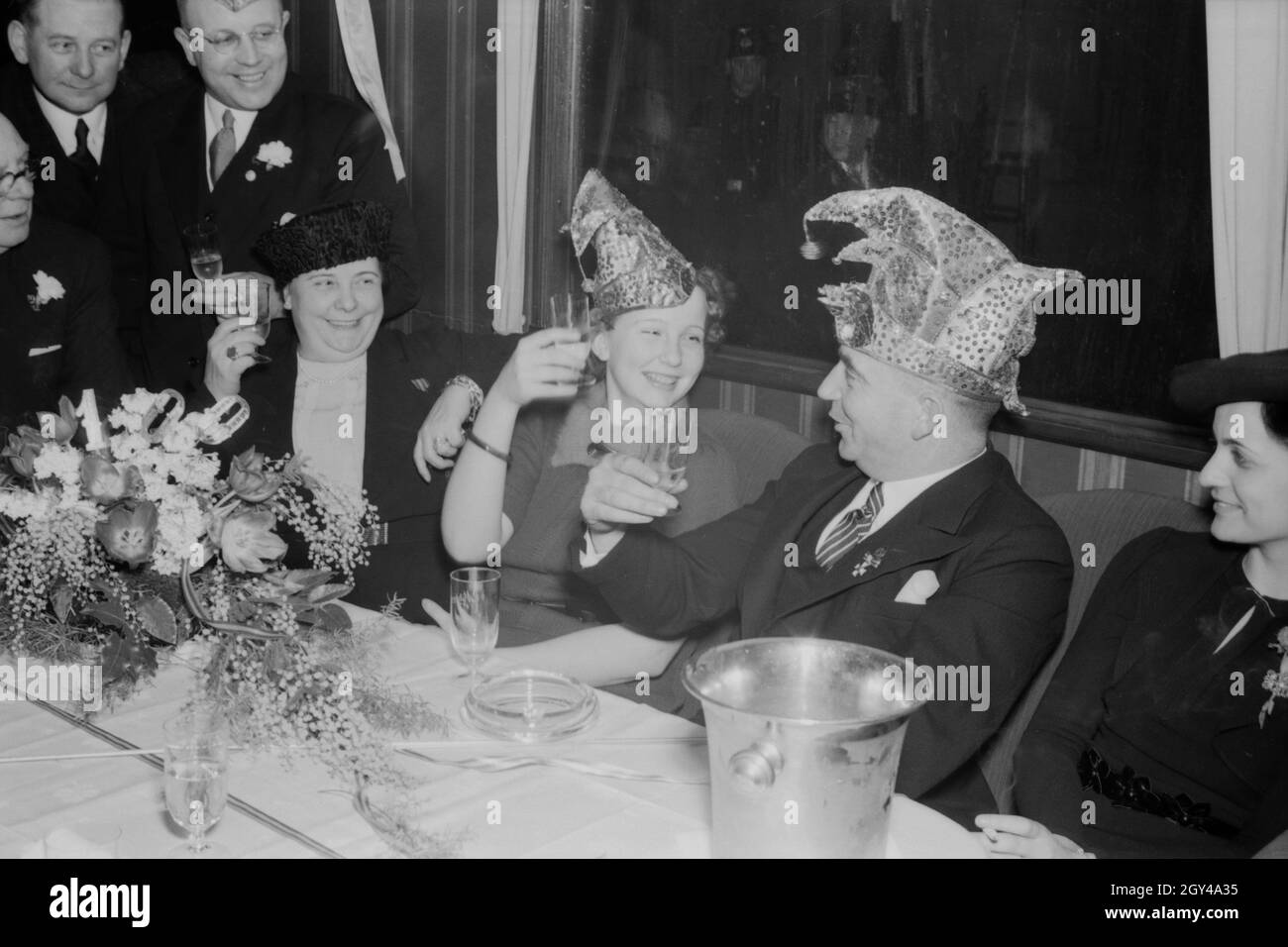 Die Prinzessin der Mainzer Fastnacht 1938, Hildegard Kühne, in fröhlicher Runde mit Seppel Glückert (?). Carnival princess Hildegard Kuehne raising her glass with Seppel Glueckert (?), 1938. Stock Photo