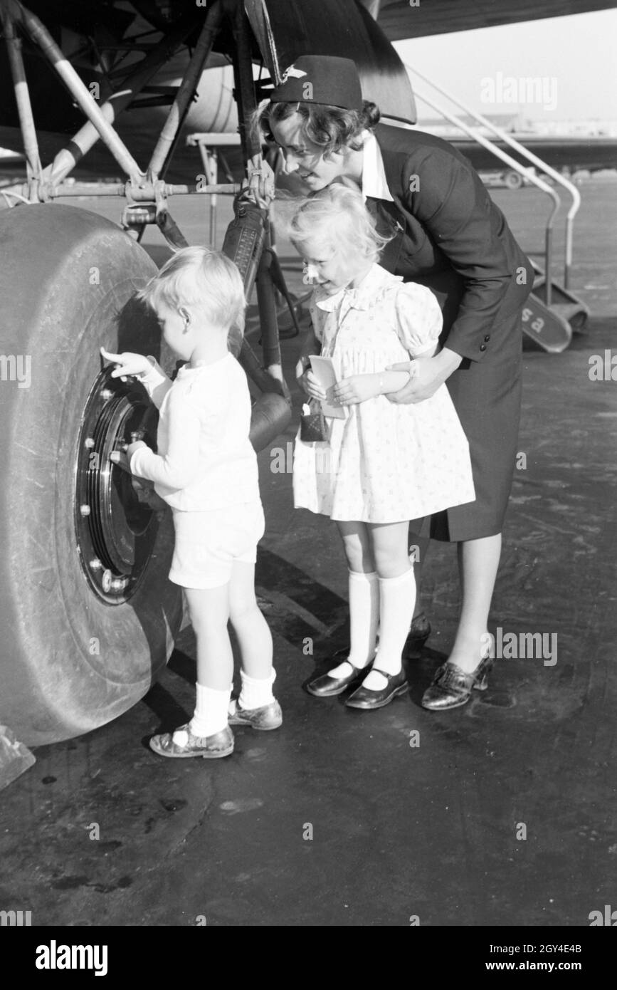 Stewardess zeigt und erklärt zwei Kindern einen Flugzeugreifen, Deutsches Reich 1930er Jahre. Stewardess showing and explaning an airplane tire to two children, Germany 1930s. Stock Photo