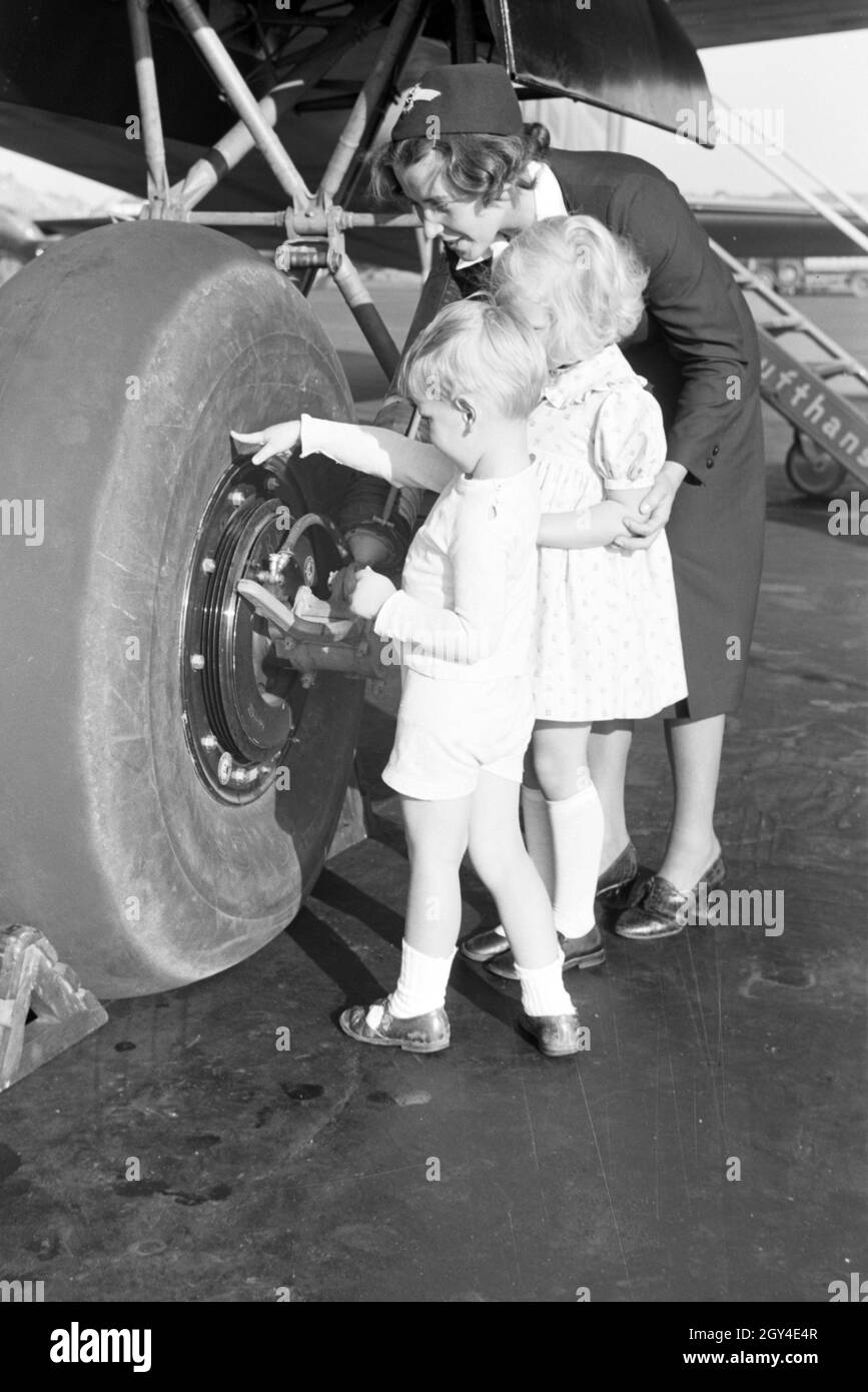 Stewardess zeigt und erklärt zwei Kindern einen Flugzeugreifen, Deutsches Reich 1930er Jahre. Stewardess showing and explaning an airplane tire to two children, Germany 1930s. Stock Photo