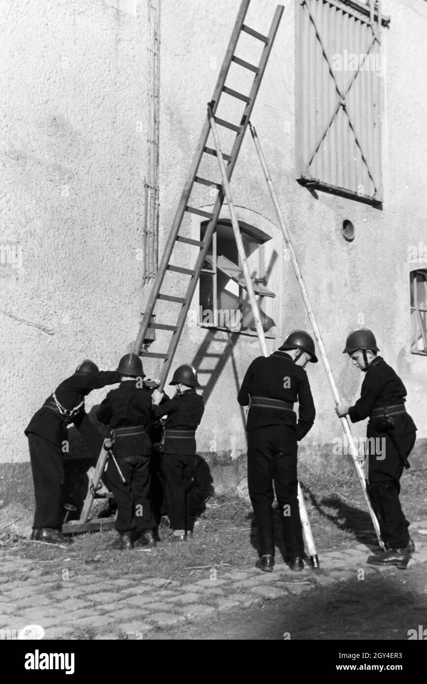 Eine Gruppe von der Kinderfeuerwehr stellt während einer Feuerwehrübung eine Leiter auf, Deutschland 1930er Jahre. A group of  junior firefighters is preparing a ladder during a firefighter training, Germany 1930s. Stock Photo