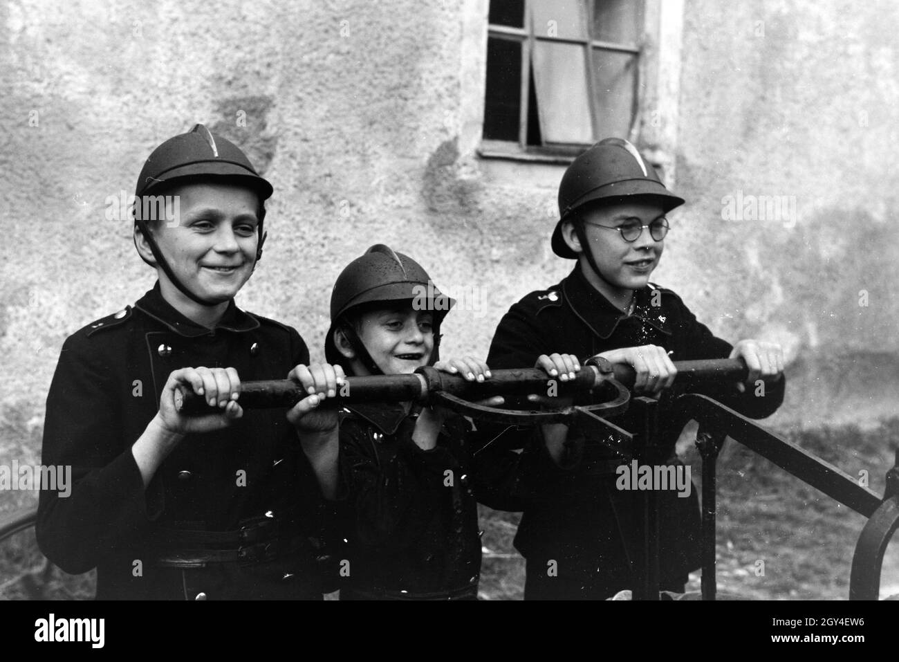 Jungen von der Kinderfeuerwehr betätigen bei einem Übungseinsatz die Wasserpumpe, Deutschland 1930er Jahre. Boys of the junior firefighters using the hand pump during a training, Germany 1930s. Stock Photo