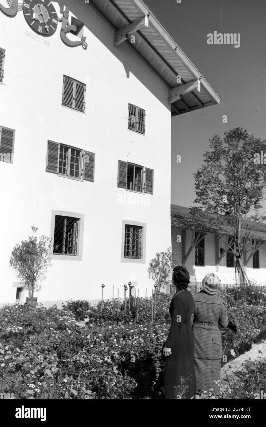 Zwei junge Frauen gehen im Garten des Rathauses am Chiemsee spazieren, Deutschland 1930er Jahre. Two young women are strolling through the city hall garden at the Chiemsee, Germany 1930s. Stock Photo