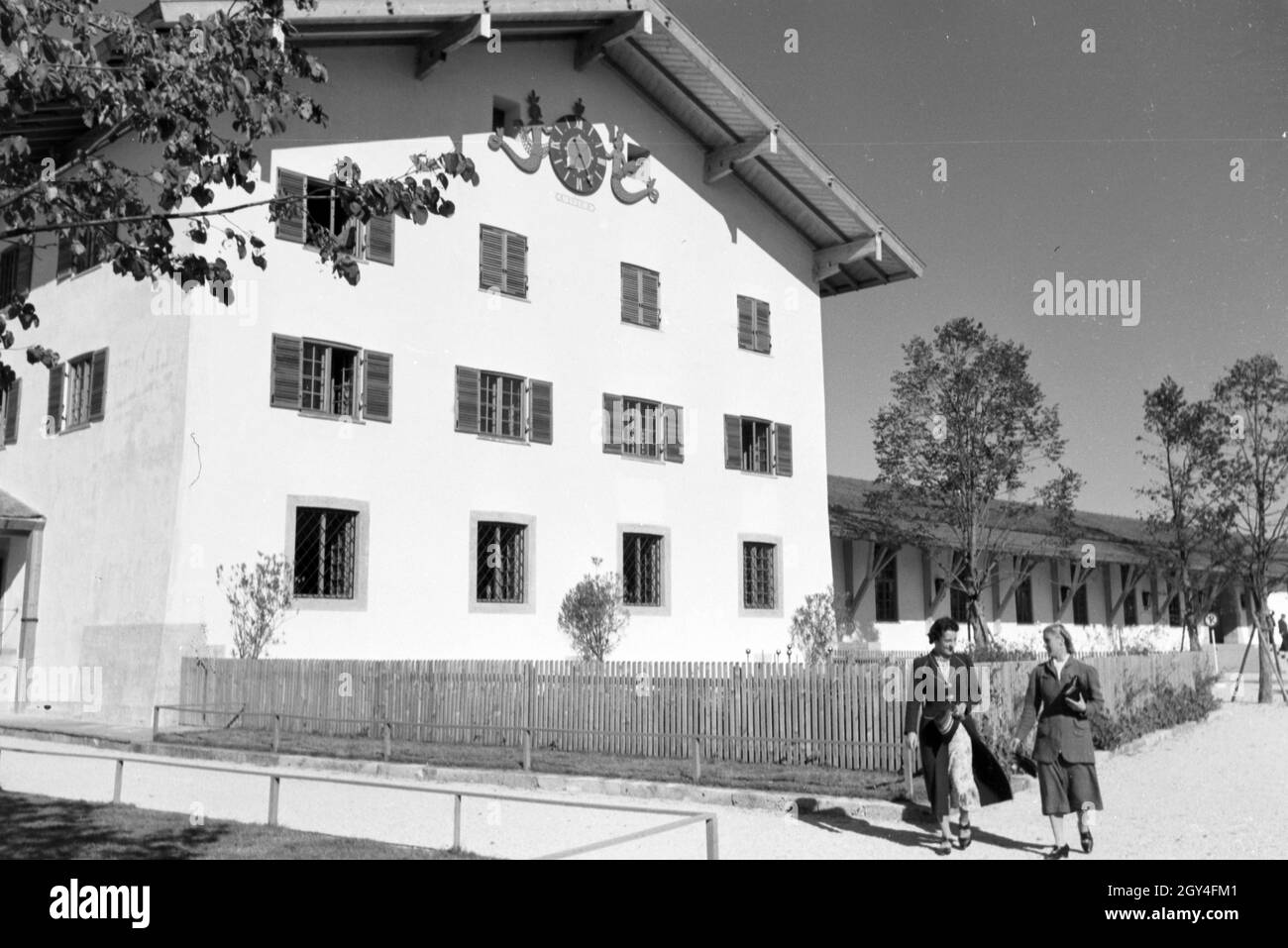Zwei junge Frauen gehen auf dem Gelände des Rathauses am Chiemsee spazieren, Deutschland 1930er Jahre. Two young women are strolling through the city hall area at the Chiemsee, Germany 1930s. Stock Photo
