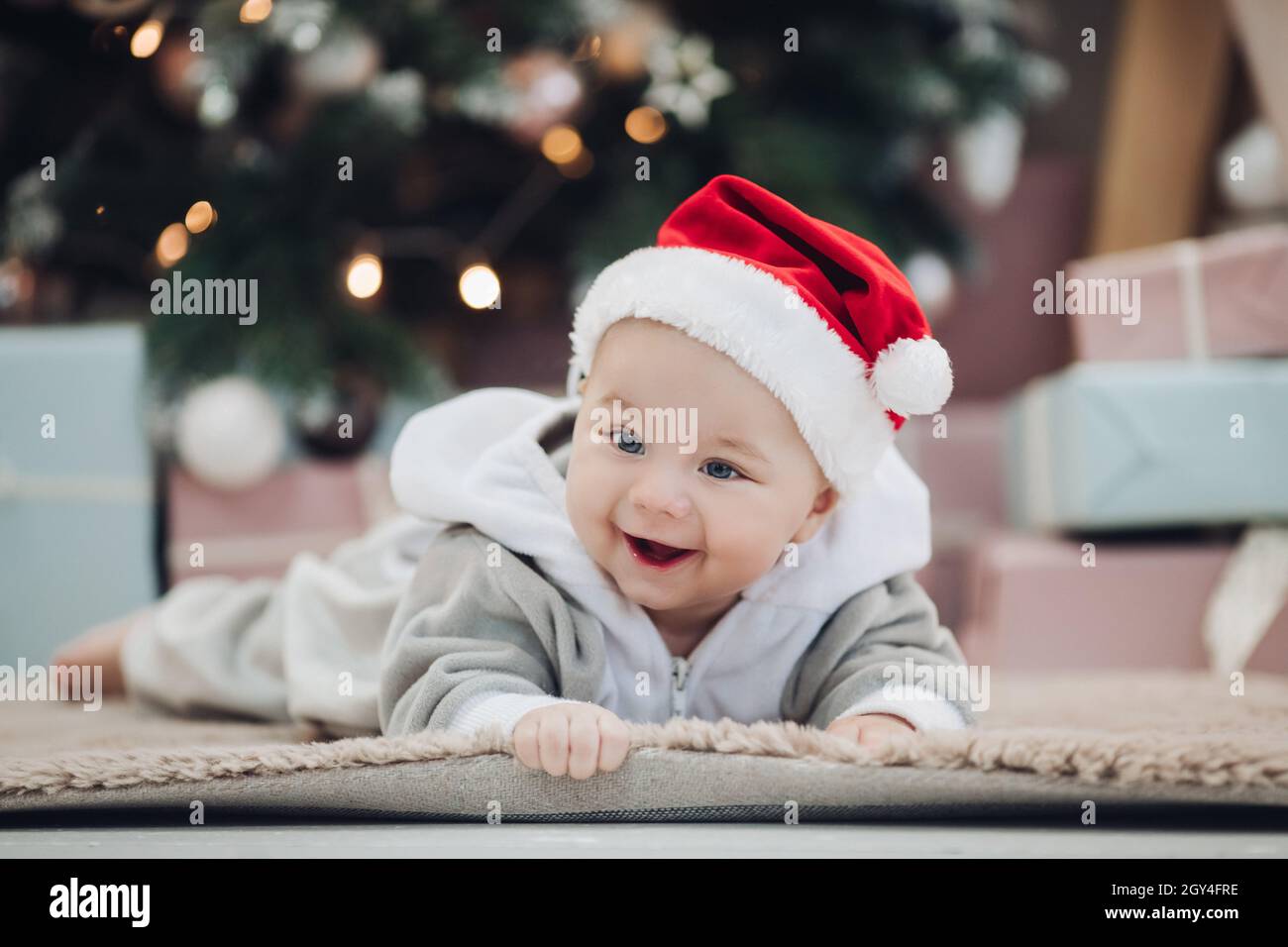 Adorable baby in red Santa hat on floor. Stock Photo