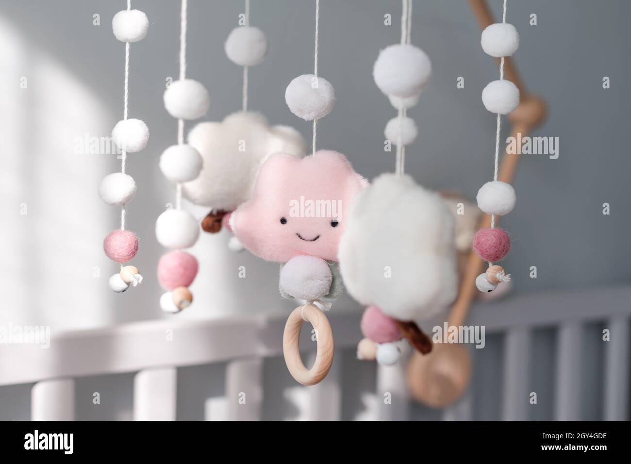 Baby crib mobile with smiling clouds and snow. Kids handmade toys above