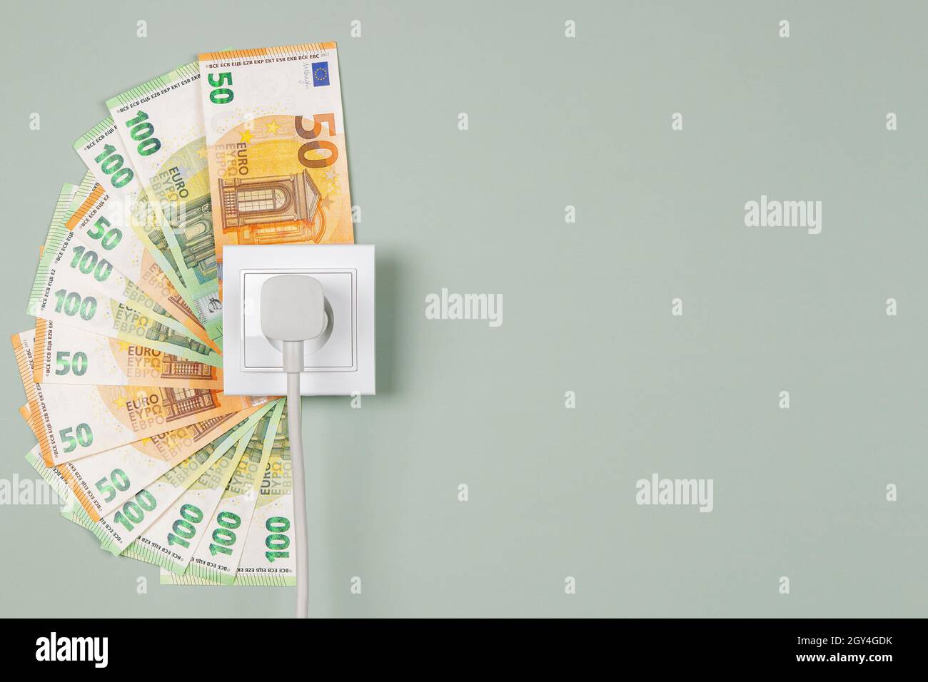 Electric socket with connected power plug and Euro banknotes arround it ...