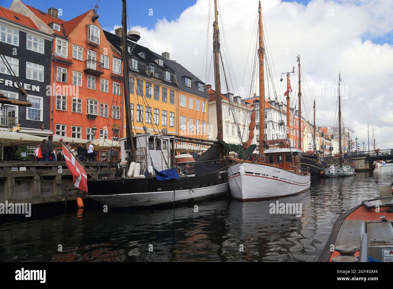 COPENHAGEN, DENMARK - JUNE 29, 2016: Old ships are located along the harbor of Nyhavn, to complement the colorfulness of this showplace. Stock Photo