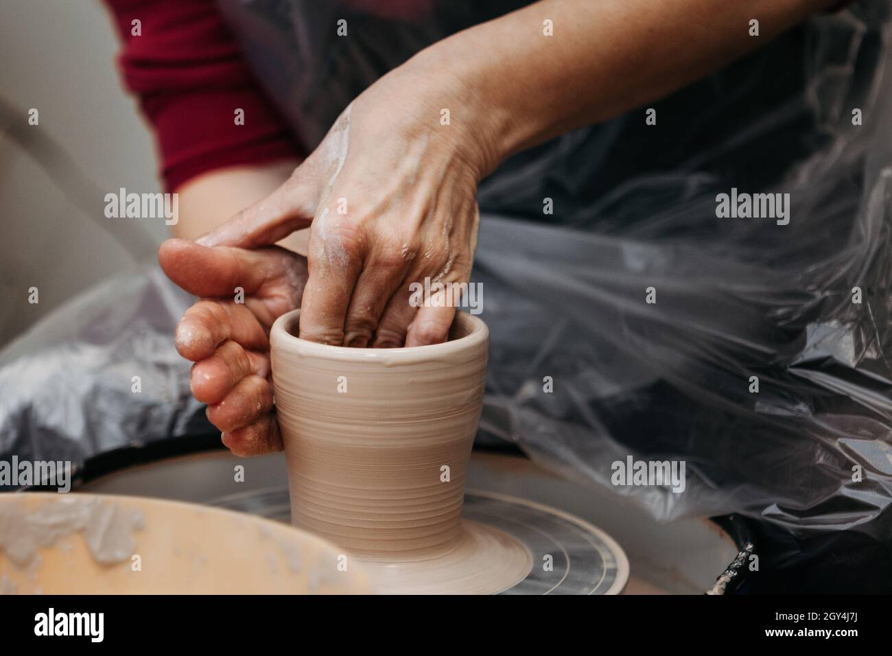 Close up of woman hands molding clay mug spinning on pottery wheel