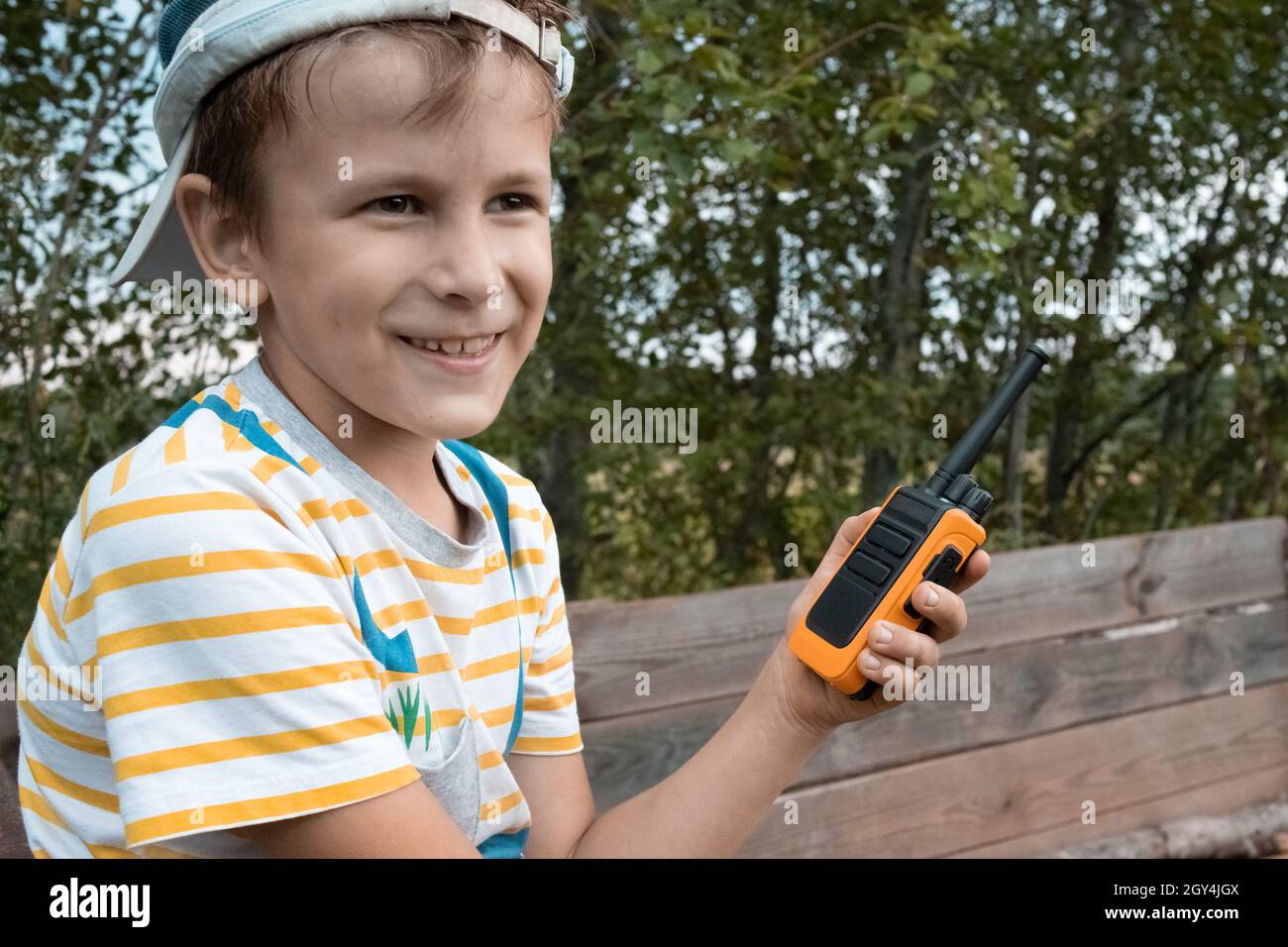Happy 8 years old boy playing outside in park with children walkie