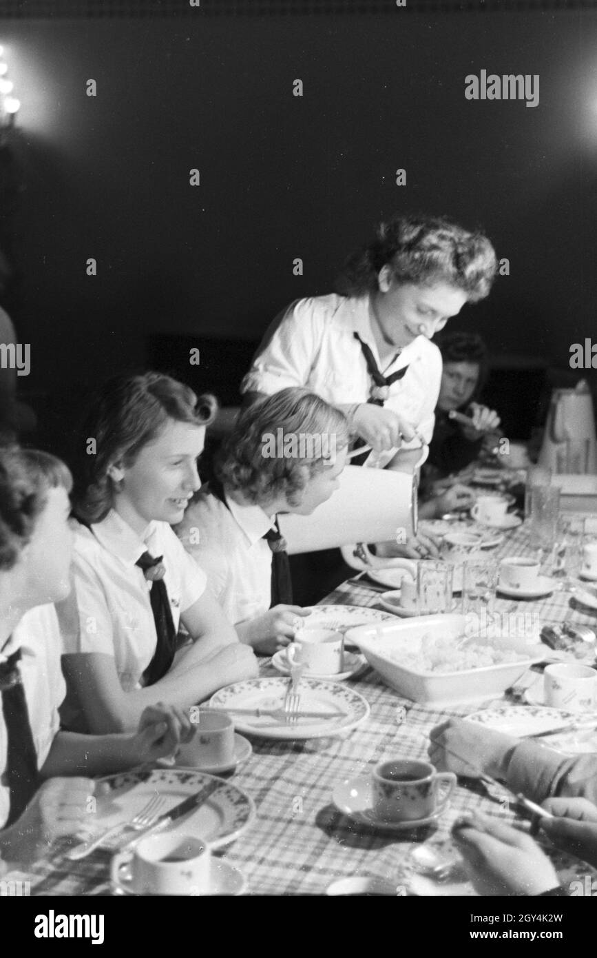 Eine Eiskunstlauf Gruppe der Hitlerjugend in den Uniformen der HJ und des BDM während des Essen nach dem Trainings, Deutschland 1930er Jahre. A figureskating group of the Hitler Youth wearing uniforms of the HJ and BDM during dinner after a training, Germany 1930s. Stock Photo